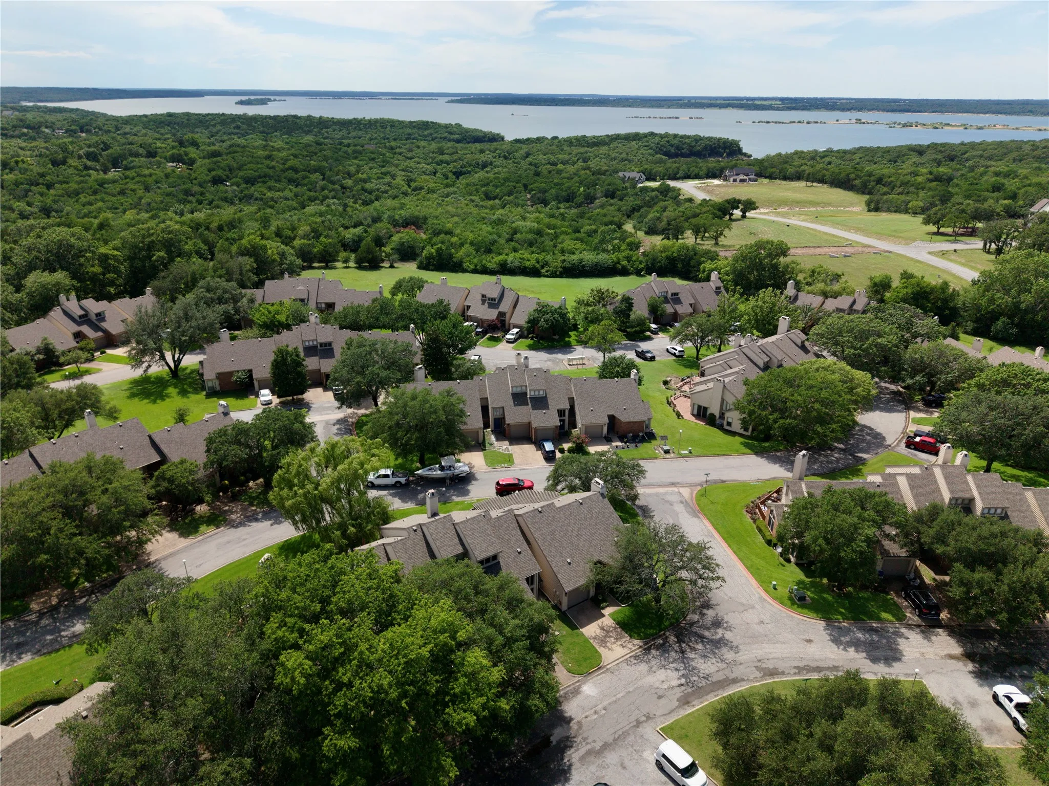 Aerial perspective showcasing a residential community surrounded by abundant green space and a prominent body of water in the distance