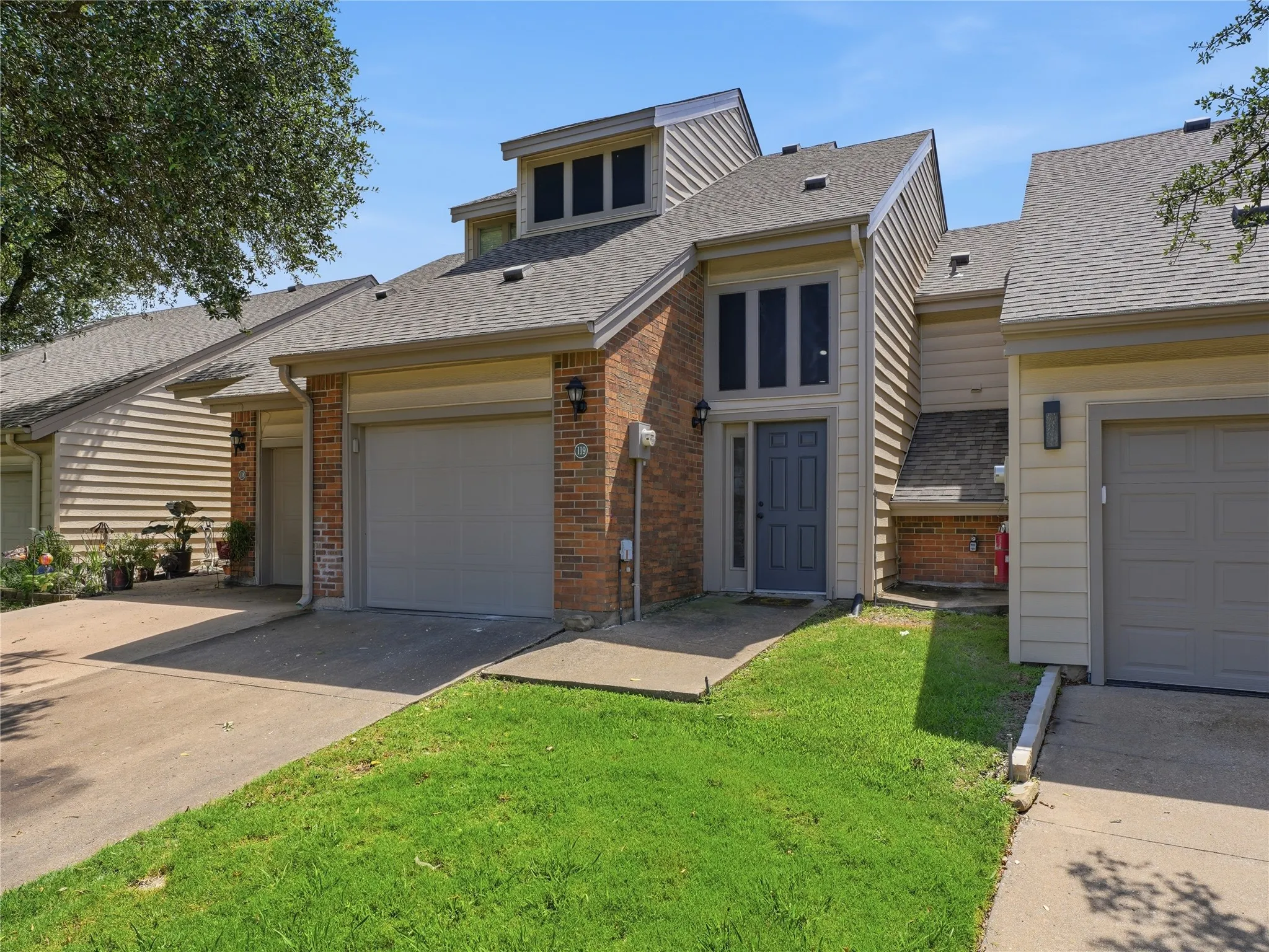 Brick facade townhome with a prominent front entrance and an attached garage