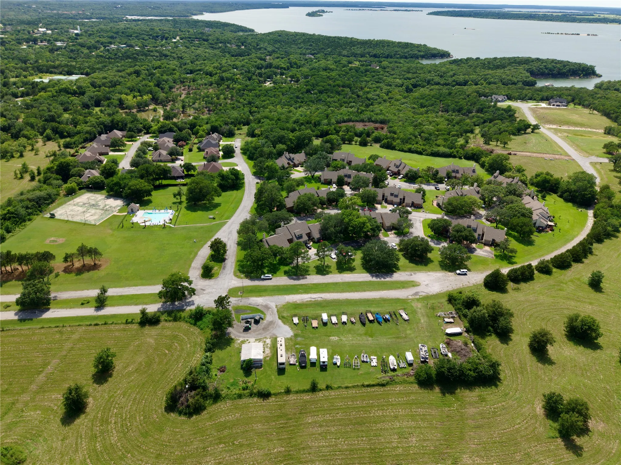 Expansive community featuring a large aquatic area, tennis courts, and varied architectural styles surrounded by mature trees
