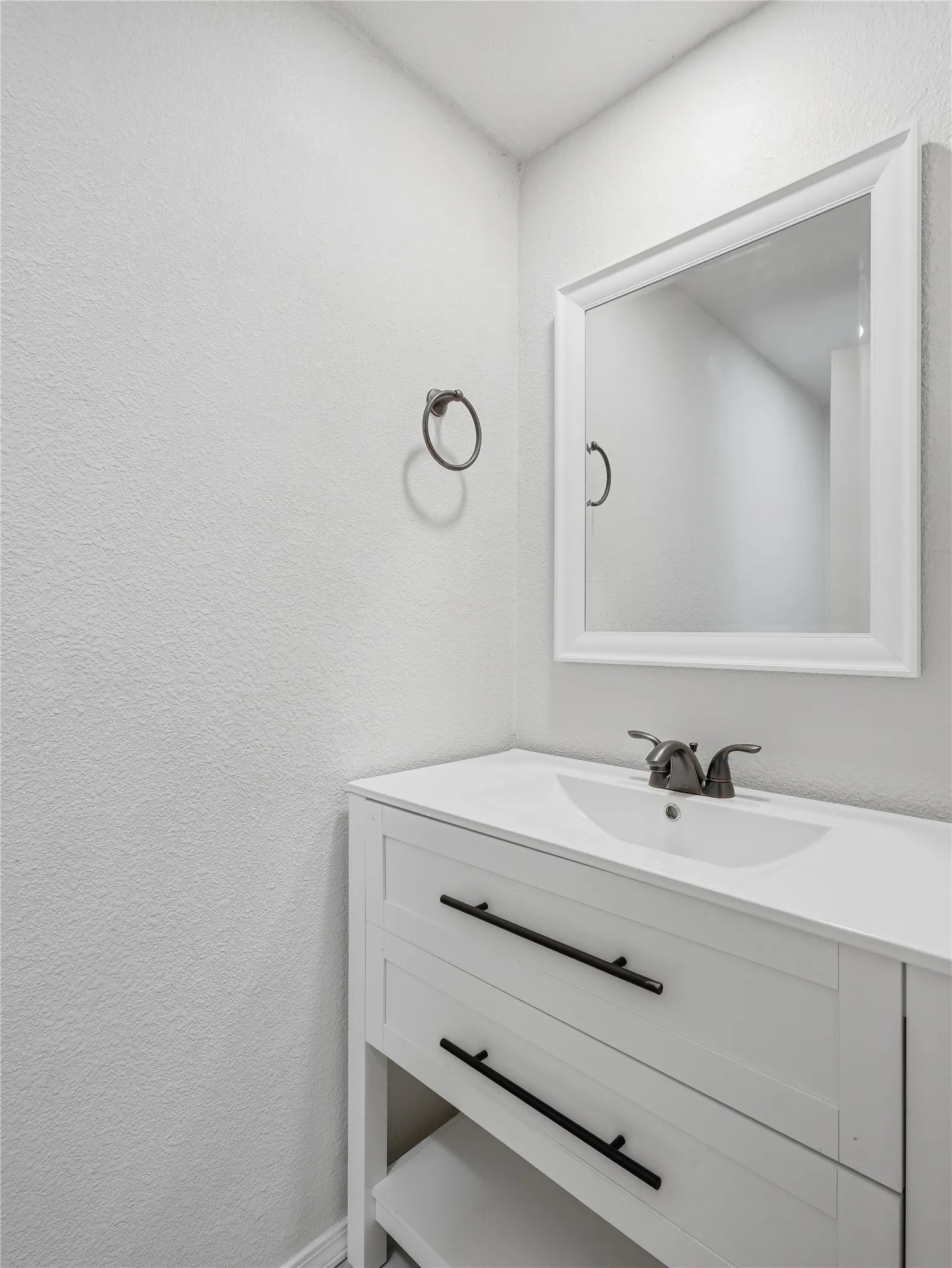 White vanity with integrated sink, dark bronze faucet, and black drawer pulls