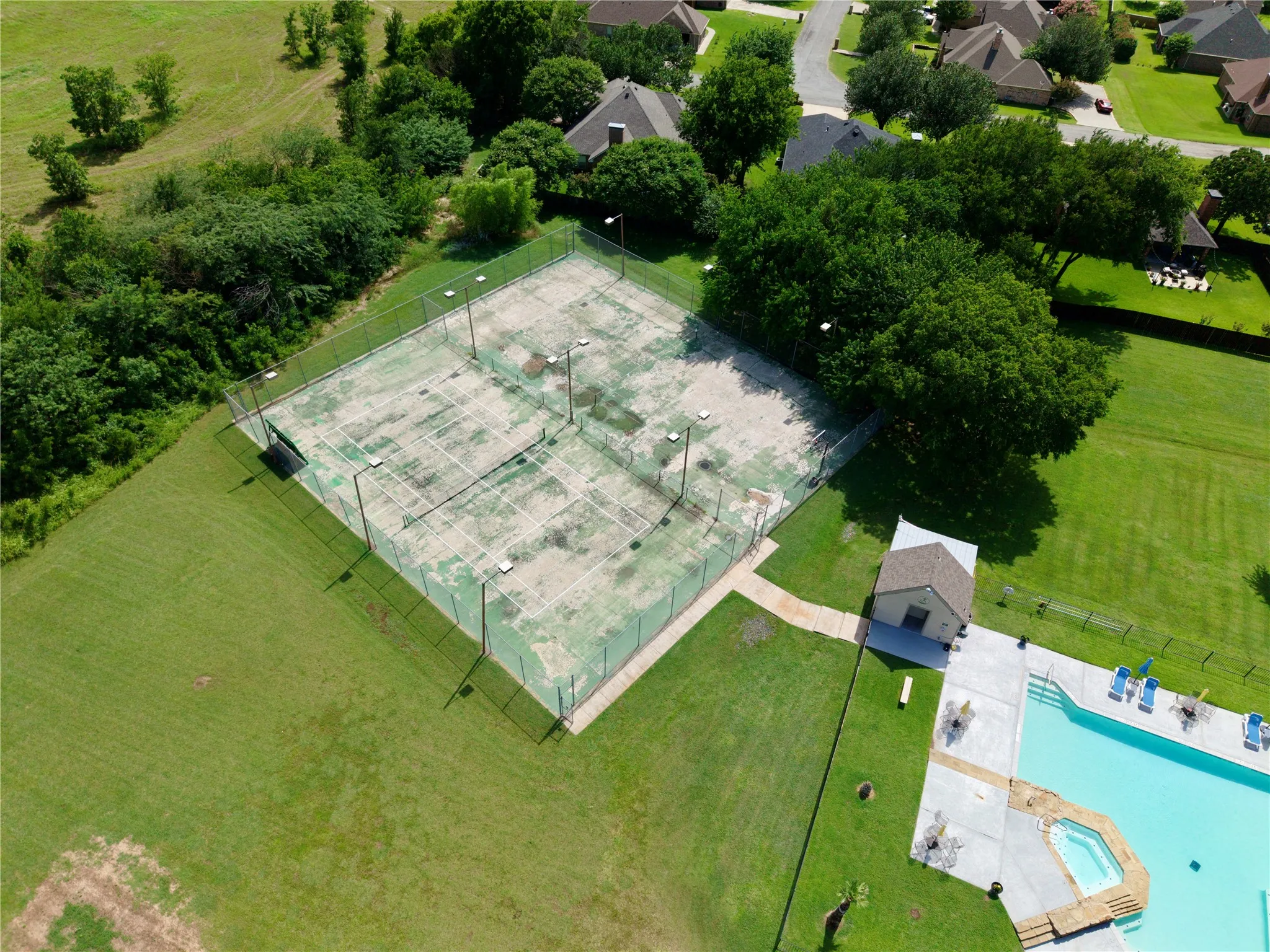 Dual tennis courts with perimeter fencing and integrated lighting