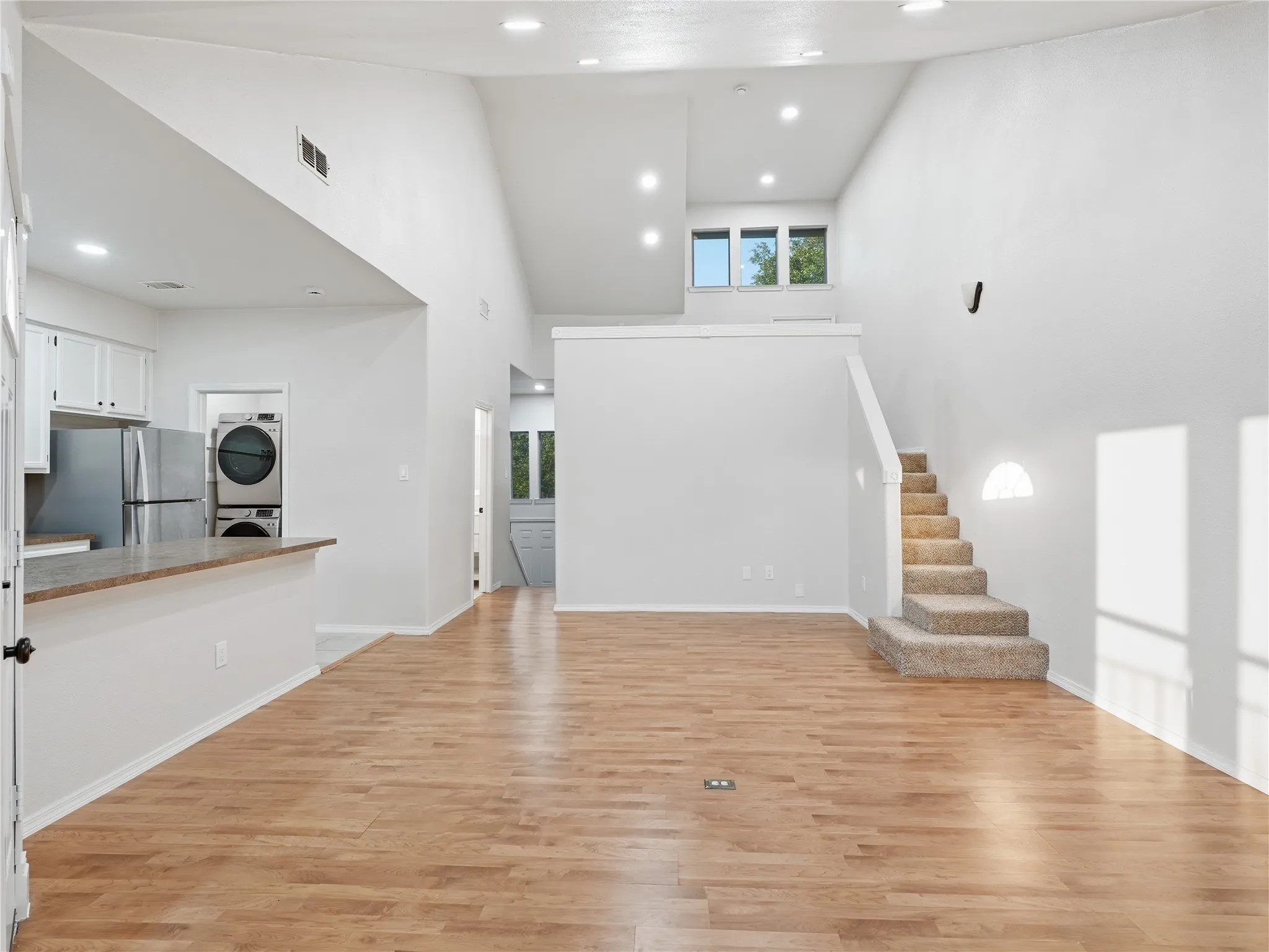 Vaulted ceilings accent an open-concept living area with wood-finish flooring