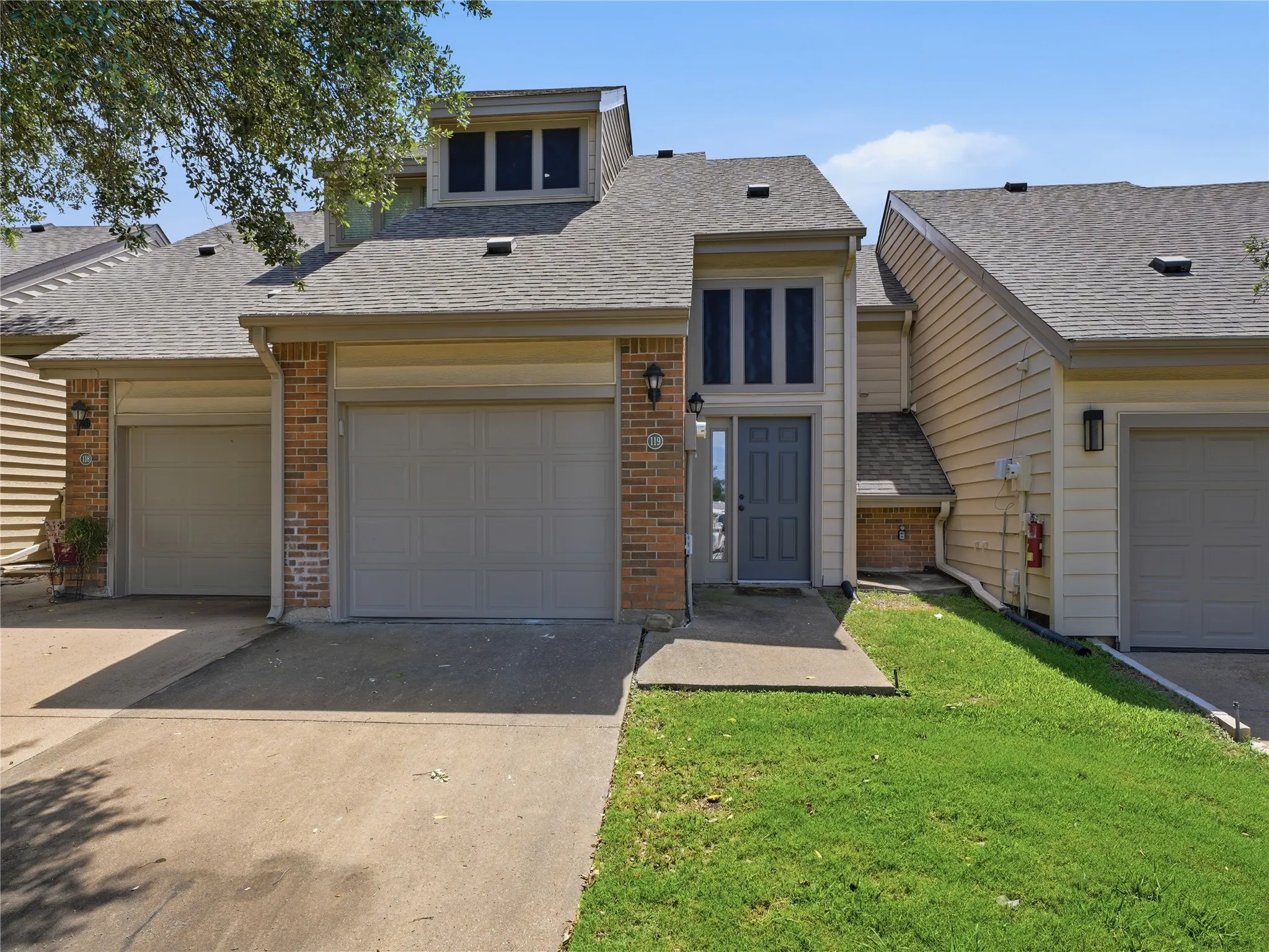 Front exterior featuring brick accents, a gray front door with side lites, and a dual garage
