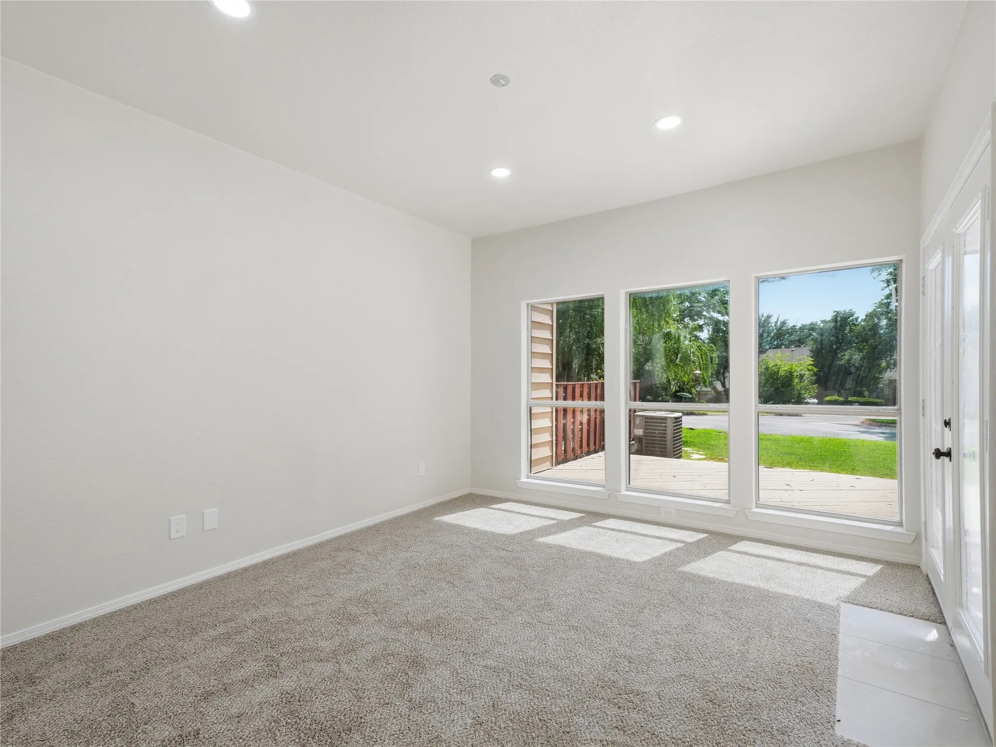 Carpeted room featuring multiple windows, recessed ceiling lighting, a vaulted ceiling, and white baseboards