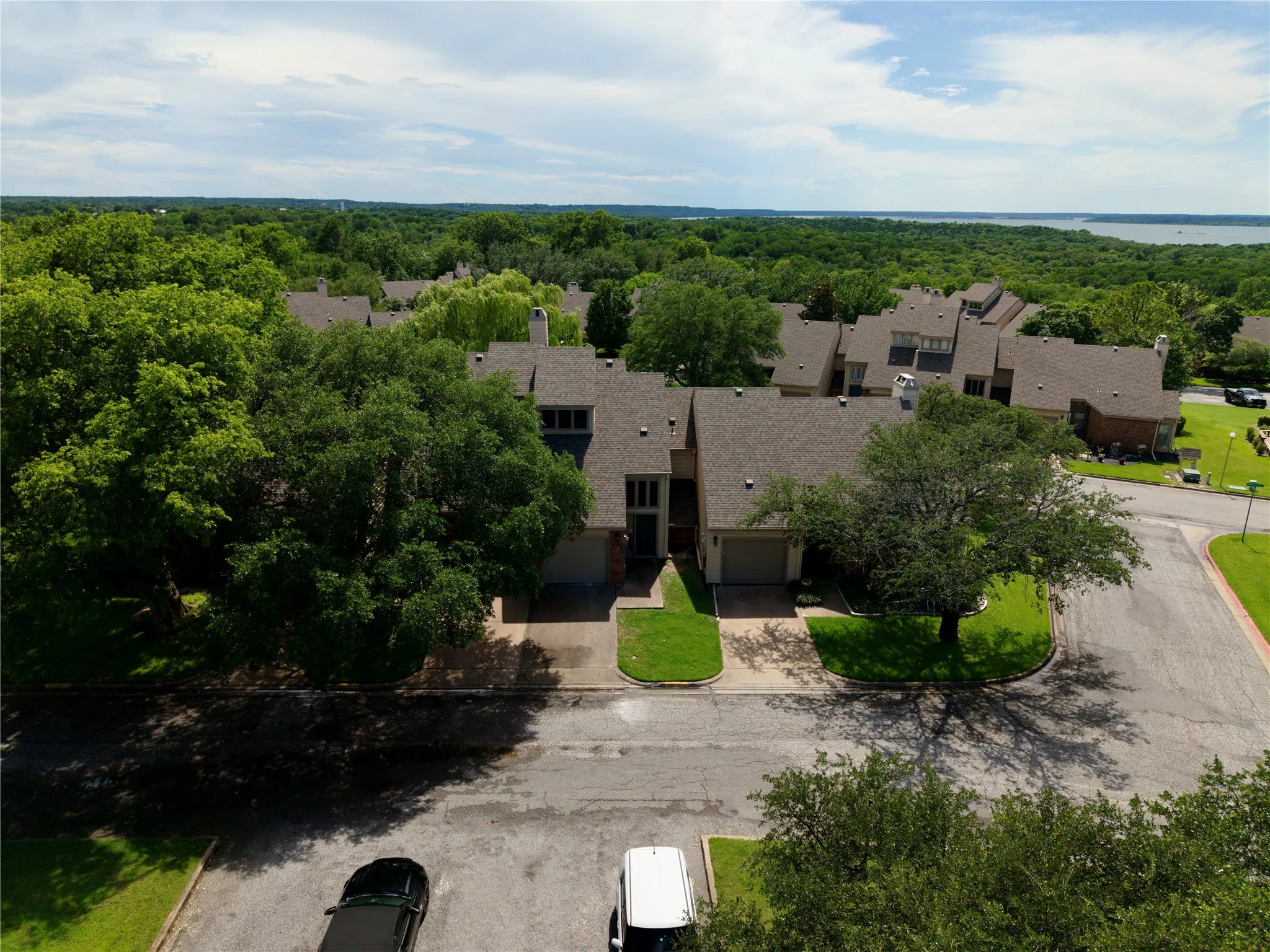 Townhome community featuring a consistent architectural style, mature tree canopies, and direct access to a paved roadway