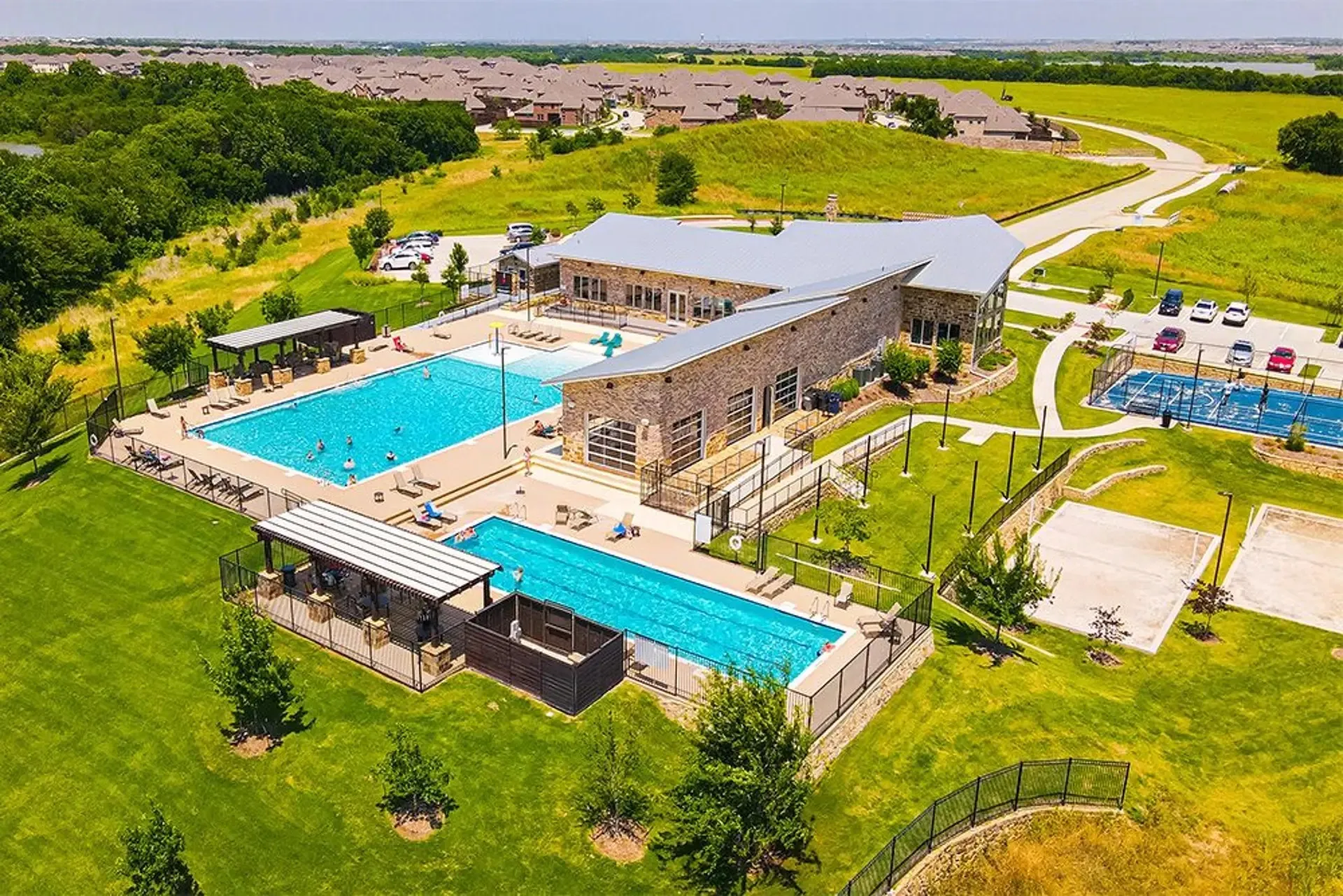 Expansive community amenity center featuring a stone-clad clubhouse with multiple pools