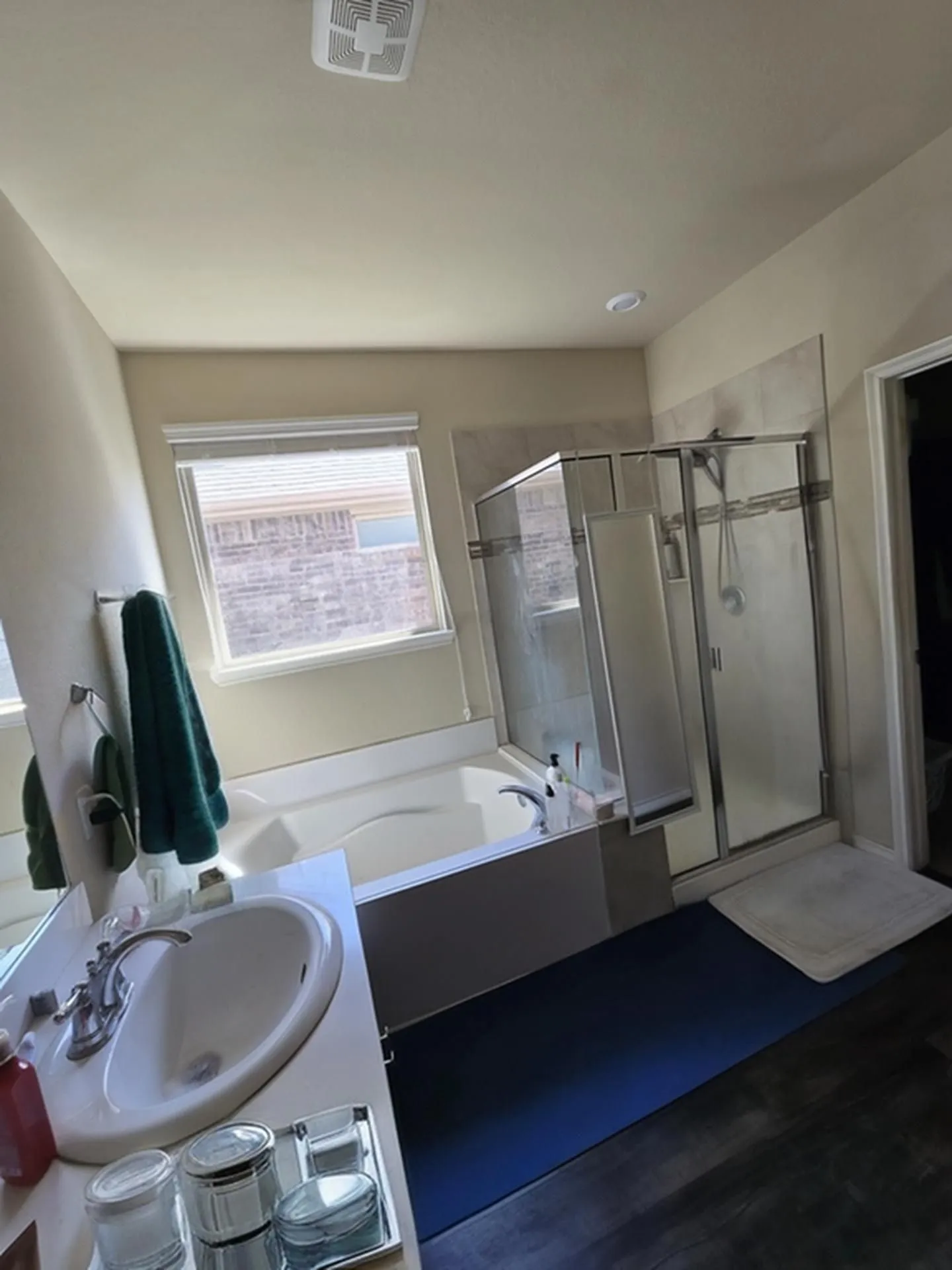 Bathroom featuring a built-in soaking tub, separate glass-enclosed shower, single vanity with oval sink, and wood-finish flooring