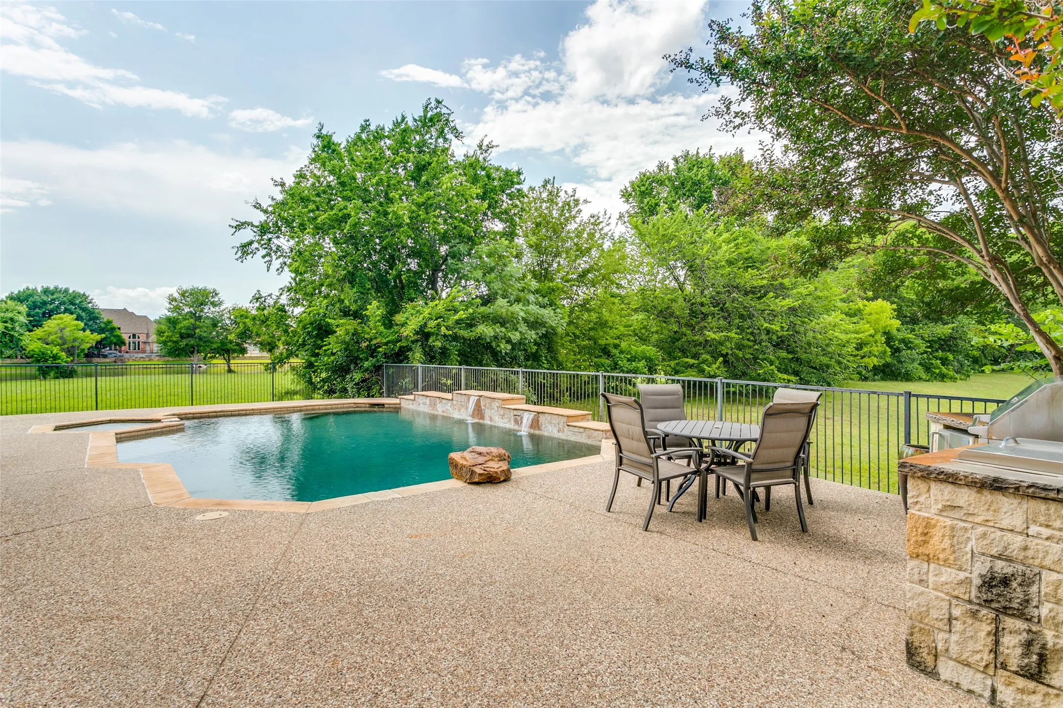 Outdoor living space featuring a freeform swimming pool with integrated spa and water features