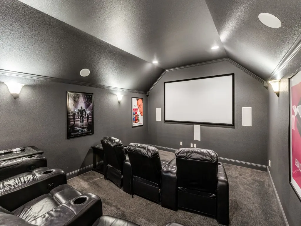 Theatre media room with sconce lighting, built-in speakers and two-level viewing.