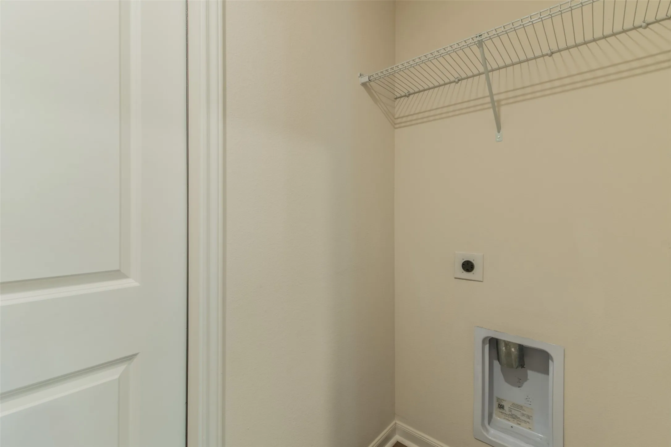 Dedicated utility area featuring a wire rack shelf, standard electrical outlet, and washer/dryer hookups