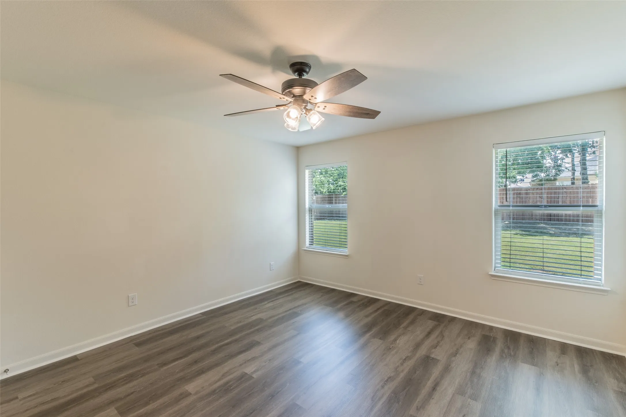 Primary bedroom neutral wall tones with luxury vinyl wood-finish flooring.