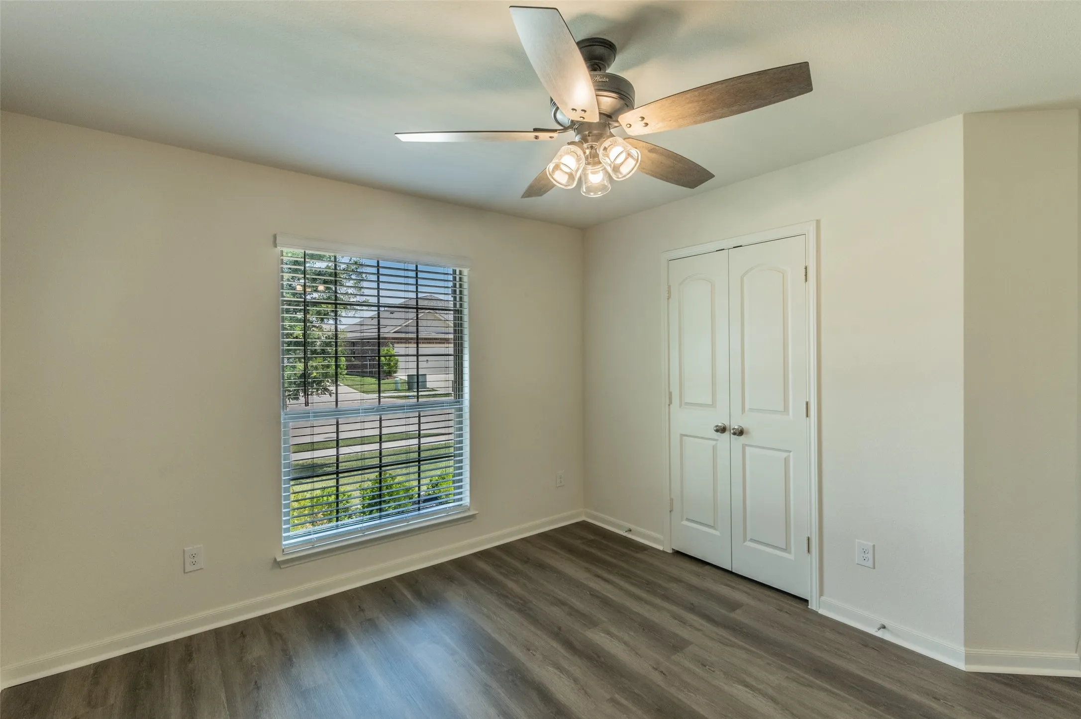 Bedroom 3 featuring luxury vinyl wood-finish flooring, a window with horizontal blinds, and a ceiling fan with integrated lighting