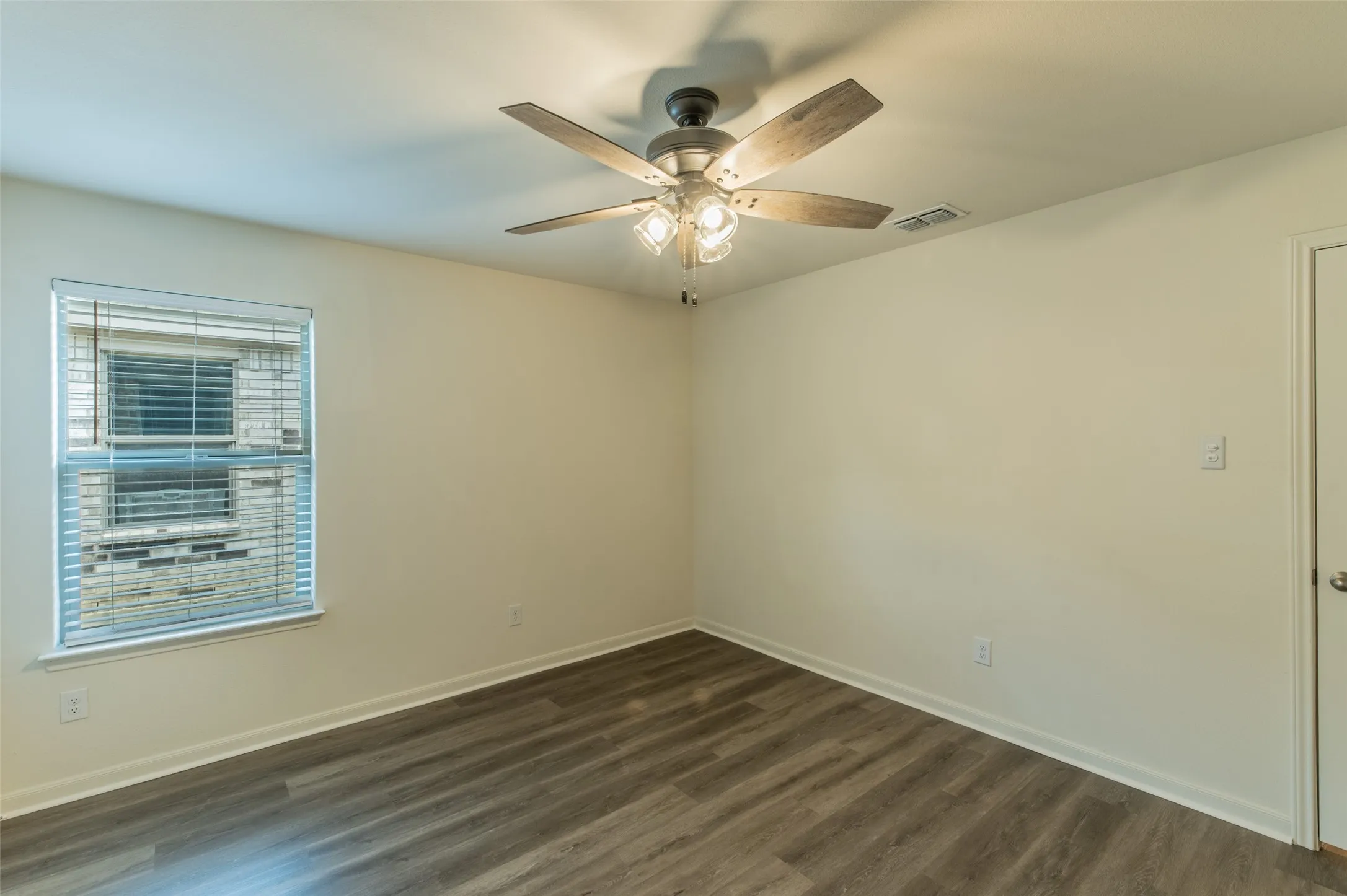 Bedroom 2 view of neutral wall paint complemented by wood-finish flooring