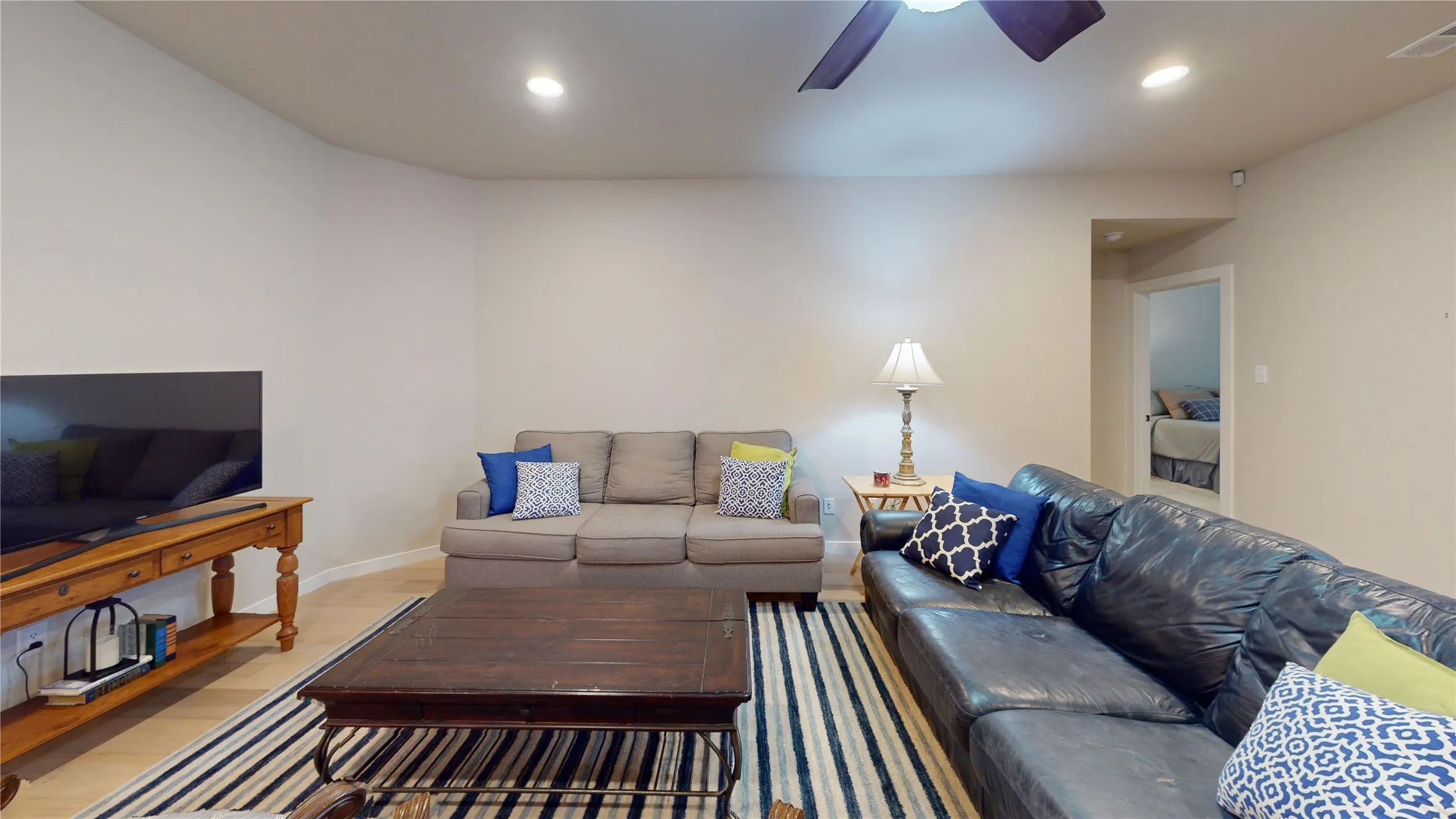 Spacious living area featuring light-toned walls, recessed lighting, and a ceiling fan