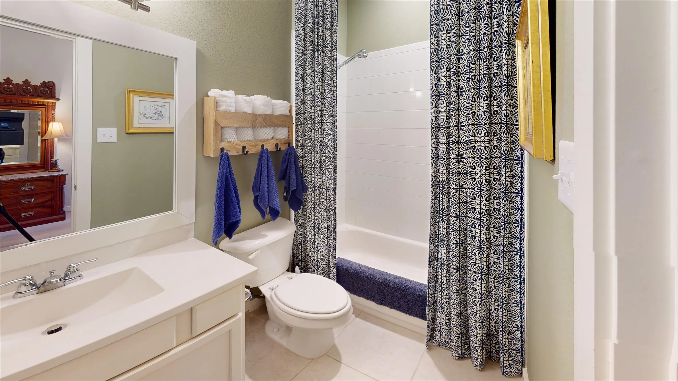 Bathroom with a white vanity featuring a single basin sink, a framed mirror, and a toilet