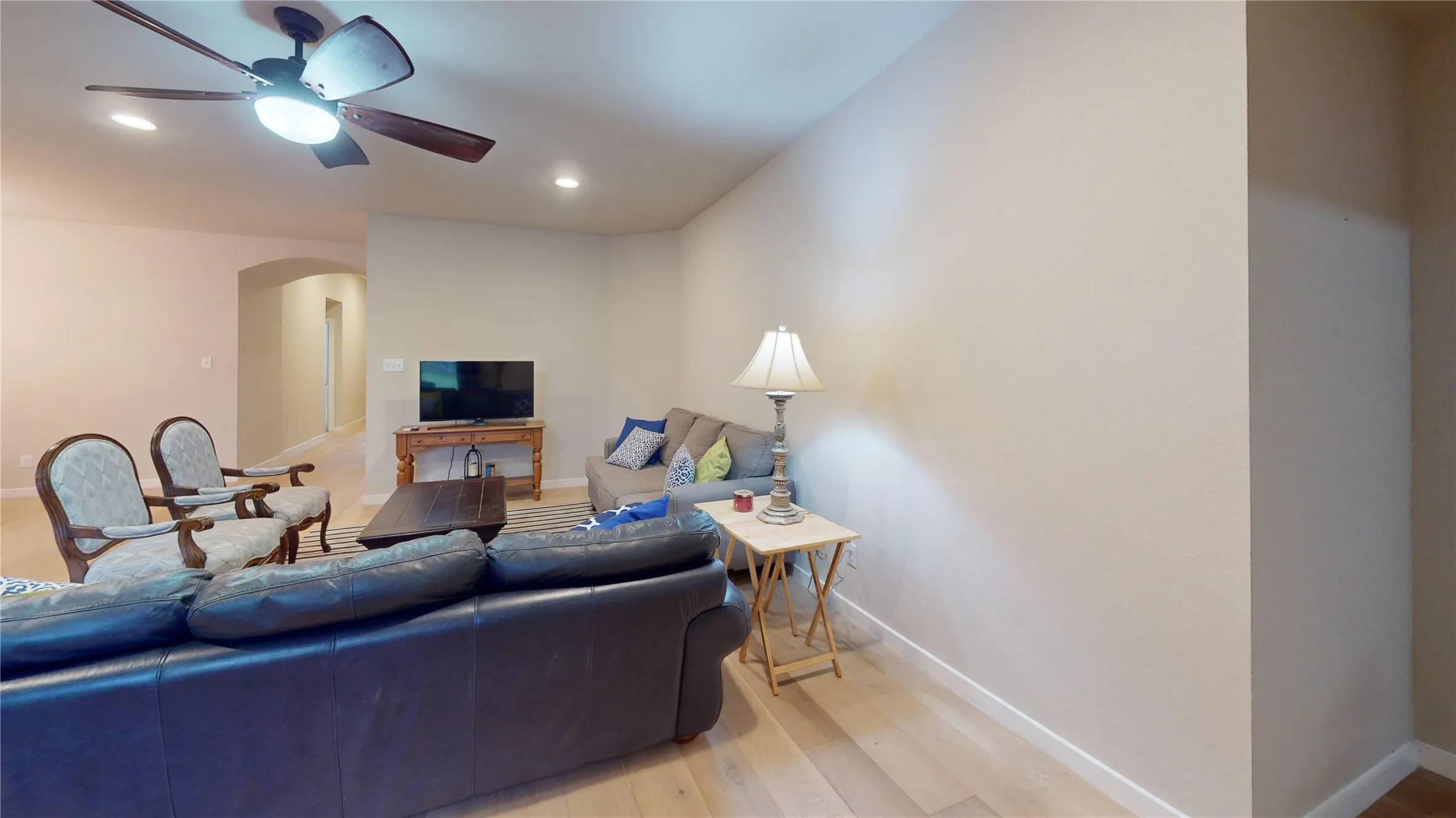 Spacious living area featuring wood-finish flooring, recessed lighting, and a ceiling fan with integrated lighting