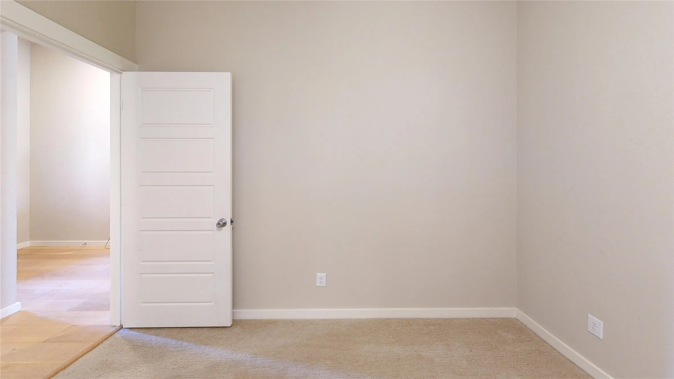 Interior space featuring light beige wall paint, white baseboards, and neutral carpet flooring