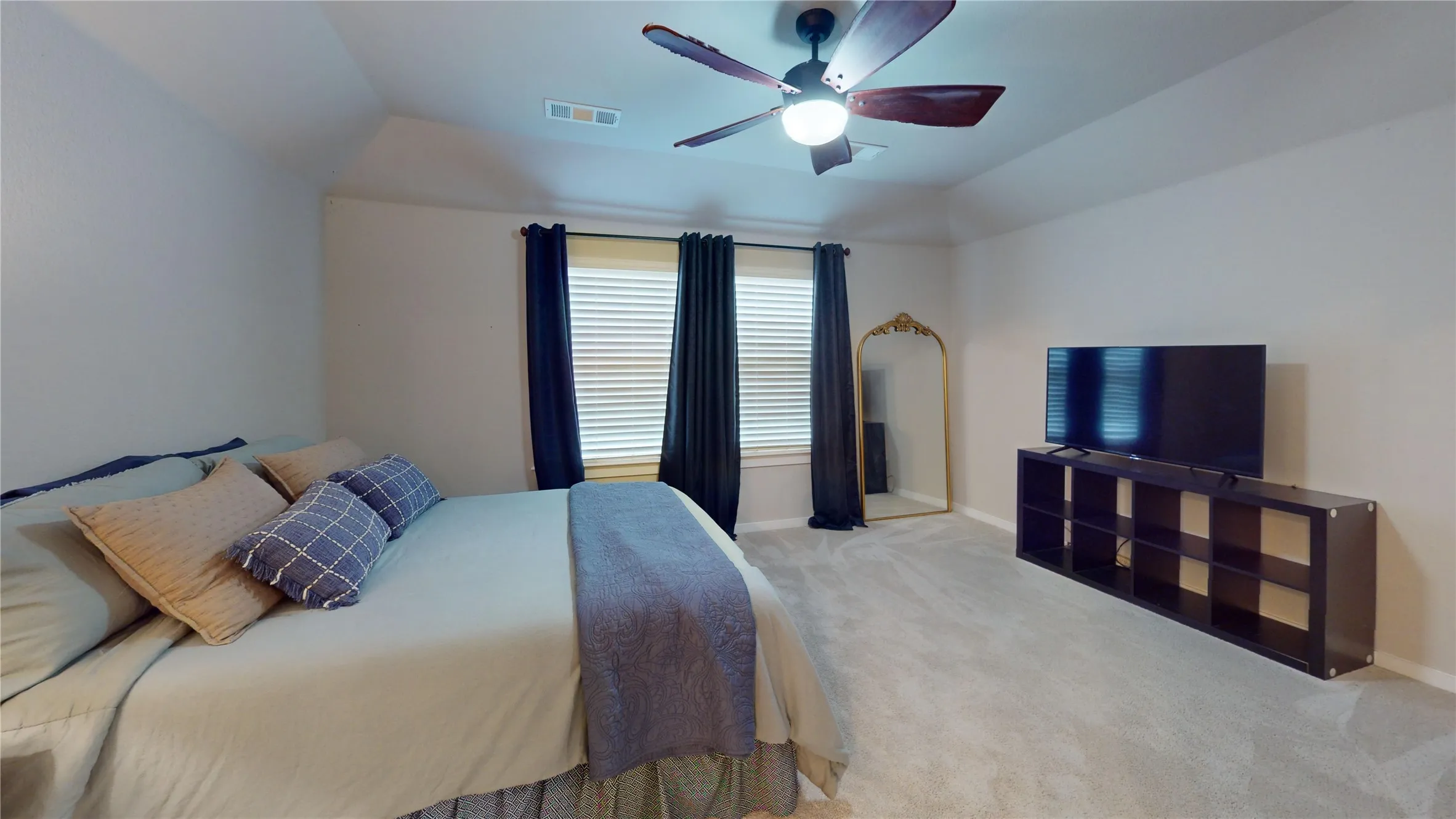 Spacious room with light-colored carpeting, a tray ceiling, and a ceiling fan with light fixture