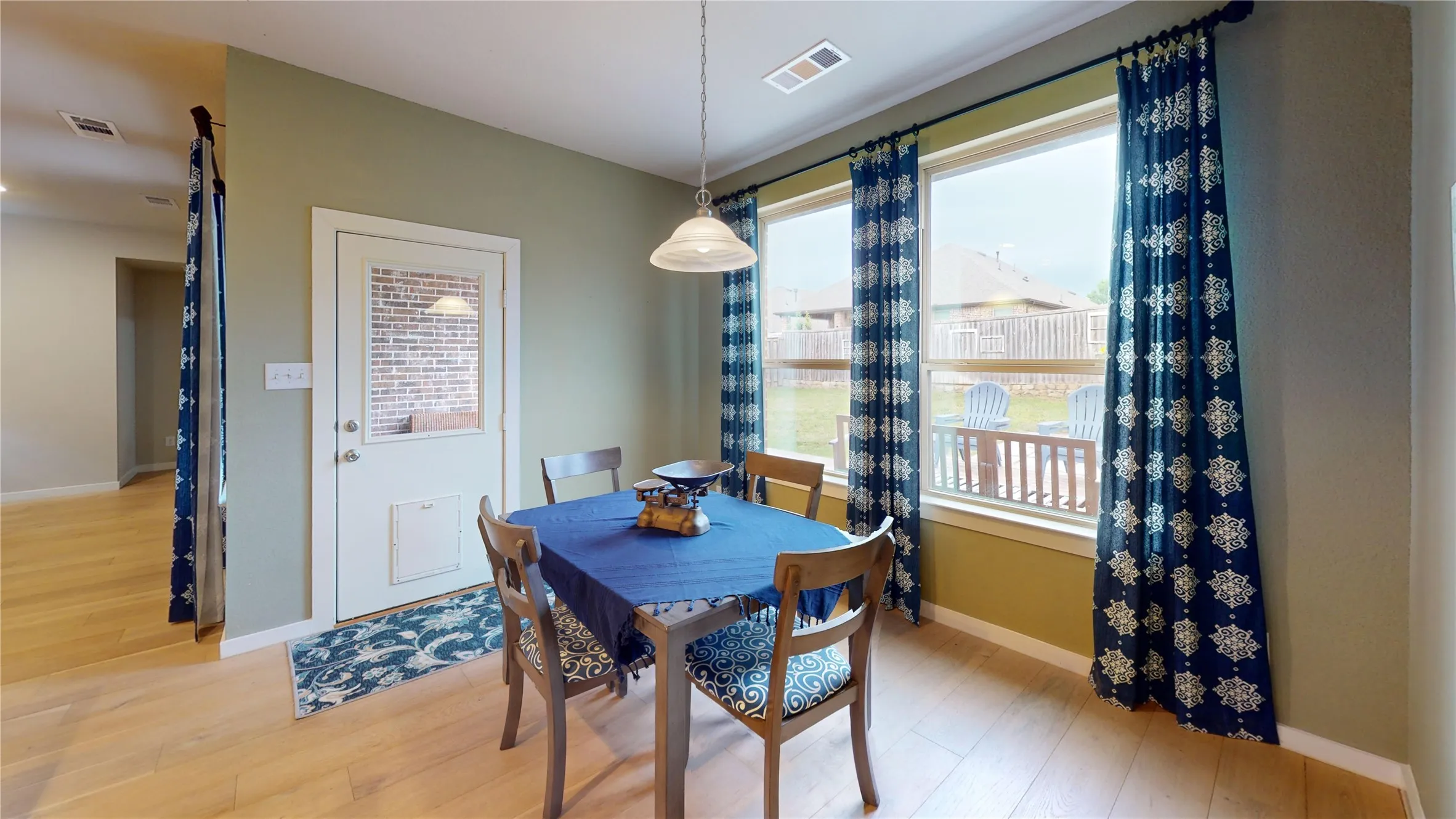 Dining area featuring wood-finish flooring, two large windows, a single-pane door with a half-light, and a ceiling-mounted pendant light fixture