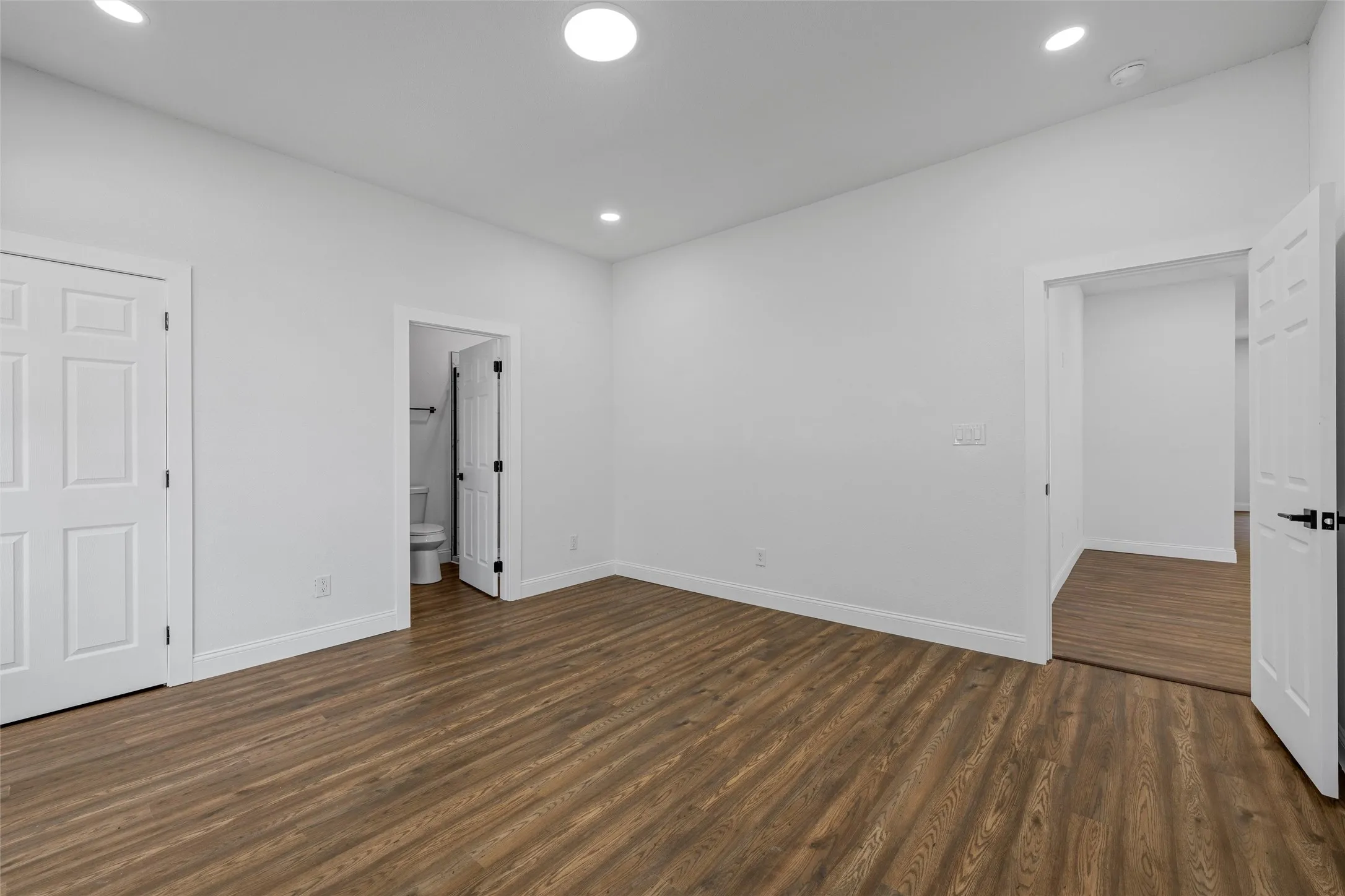 Spacious room featuring wood-finish flooring, white walls, and recessed lighting