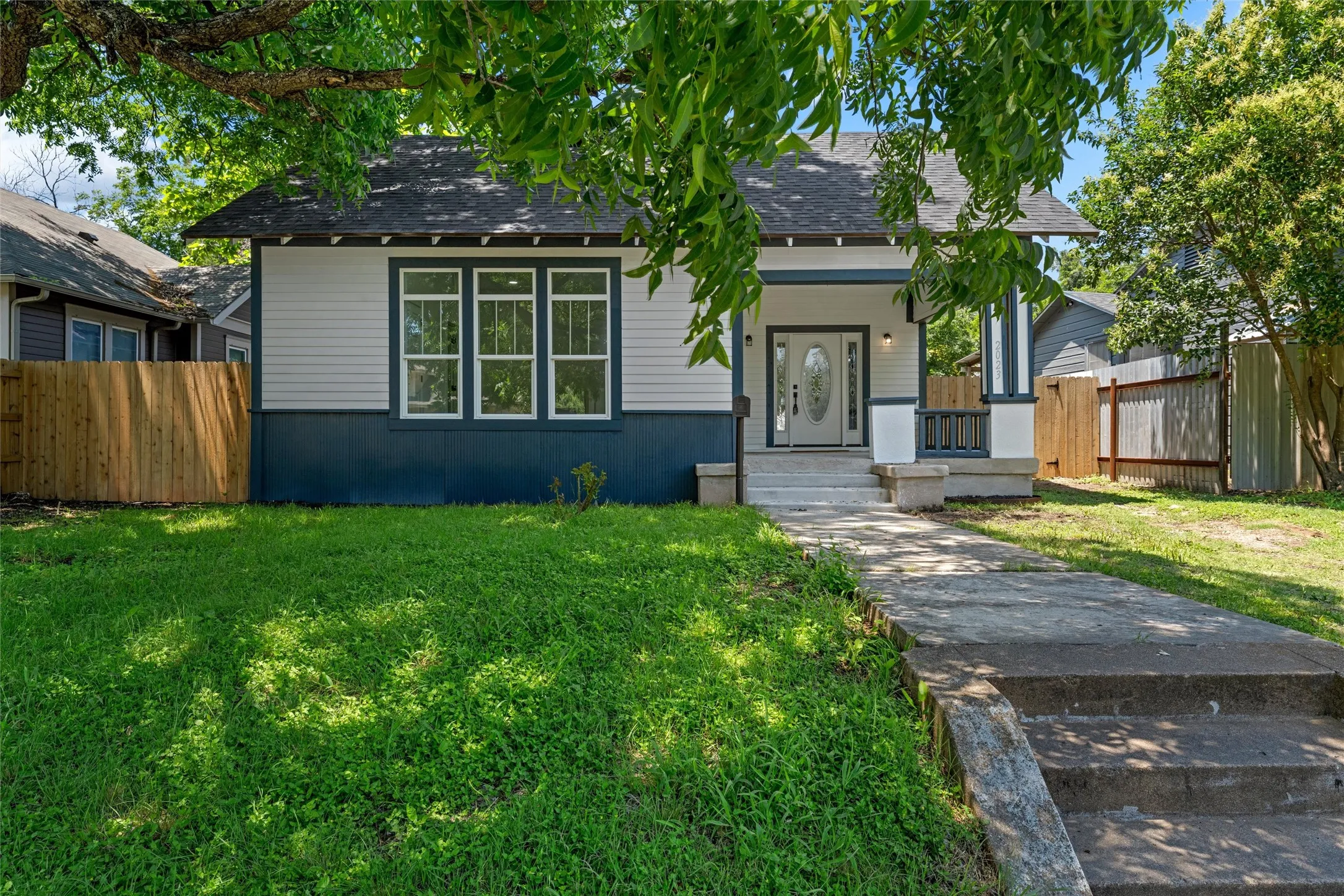 Classic bungalow featuring a covered front porch, white-paneled front door with decorative glass inlay, and a multi-pane window configuration
