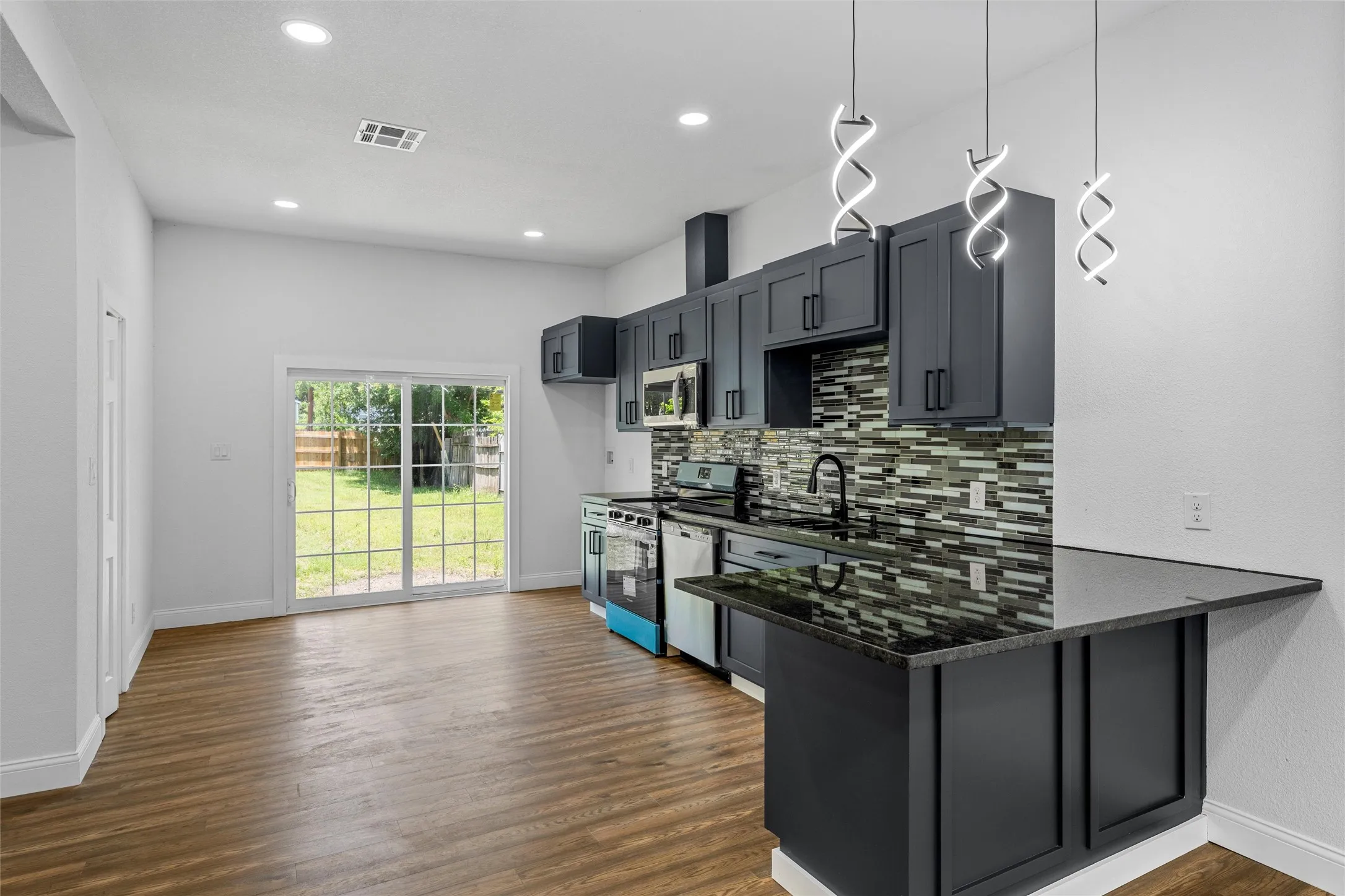 Modern kitchen featuring dark cabinetry, dark countertops, and a full tile backsplash