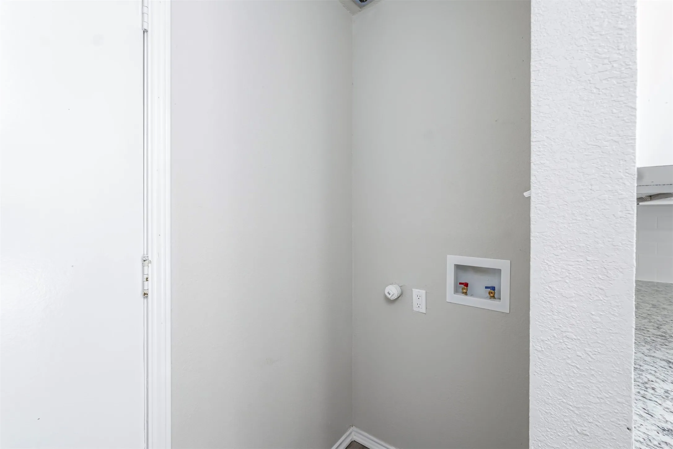 Dedicated utility area with light grey walls, white baseboards, and wood-finish flooring