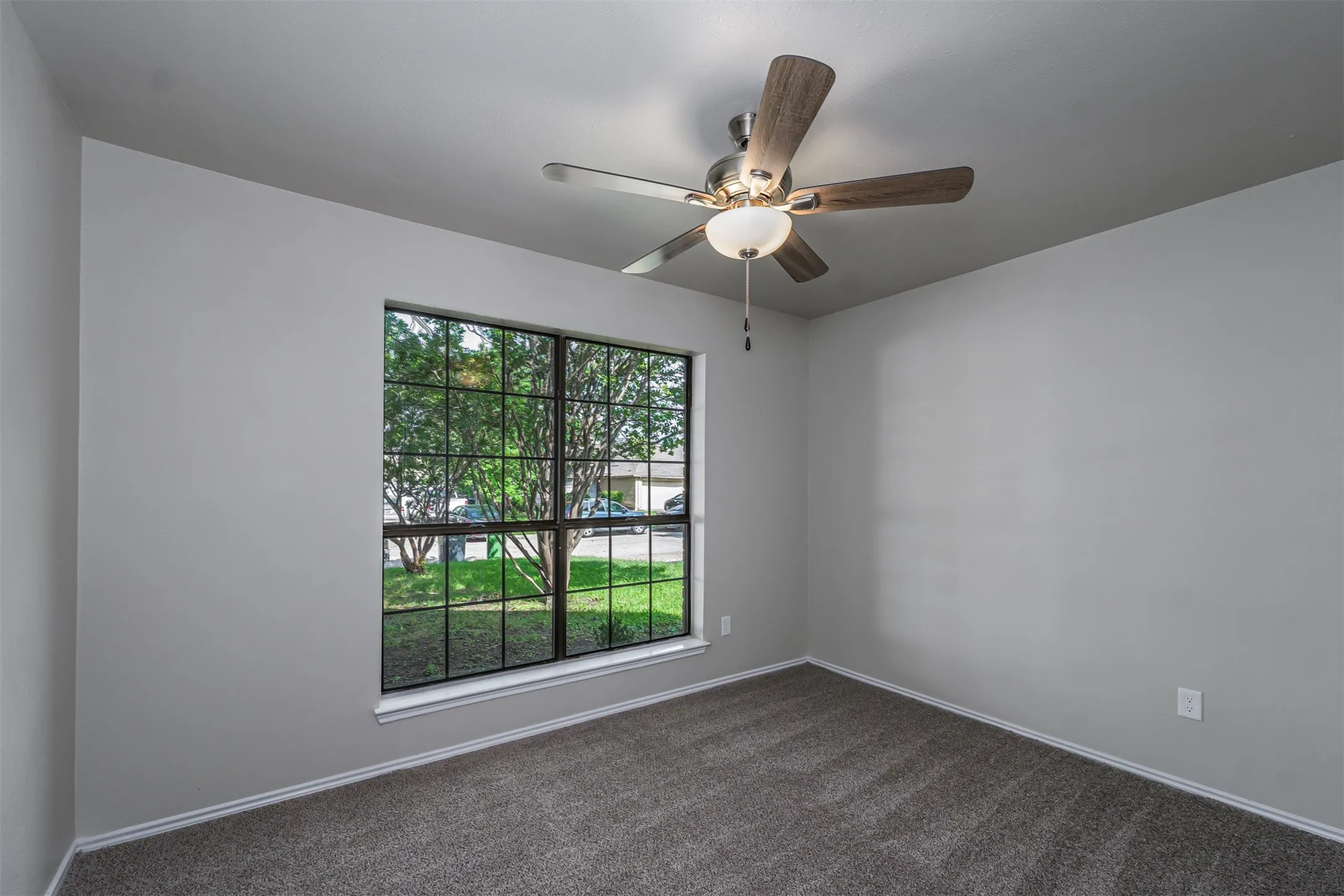 Room with light gray walls, dark gray carpet, and white baseboards