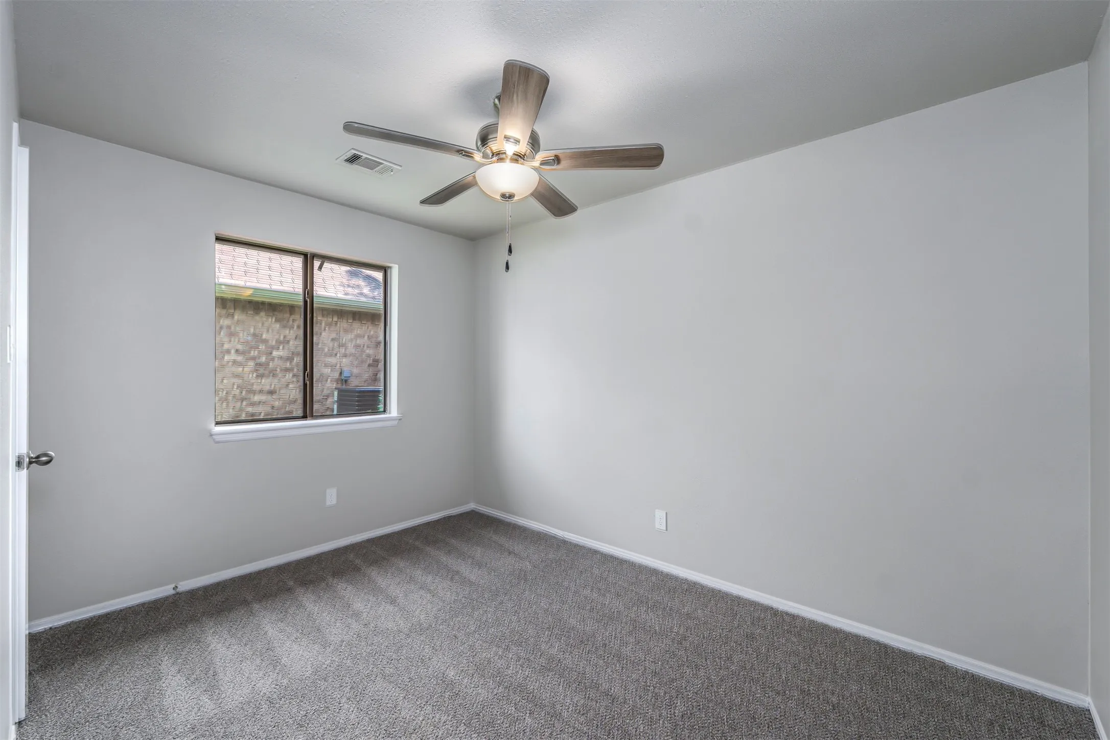 Bedroom featuring light gray wall paint, gray patterned carpet, and a window with a white frame