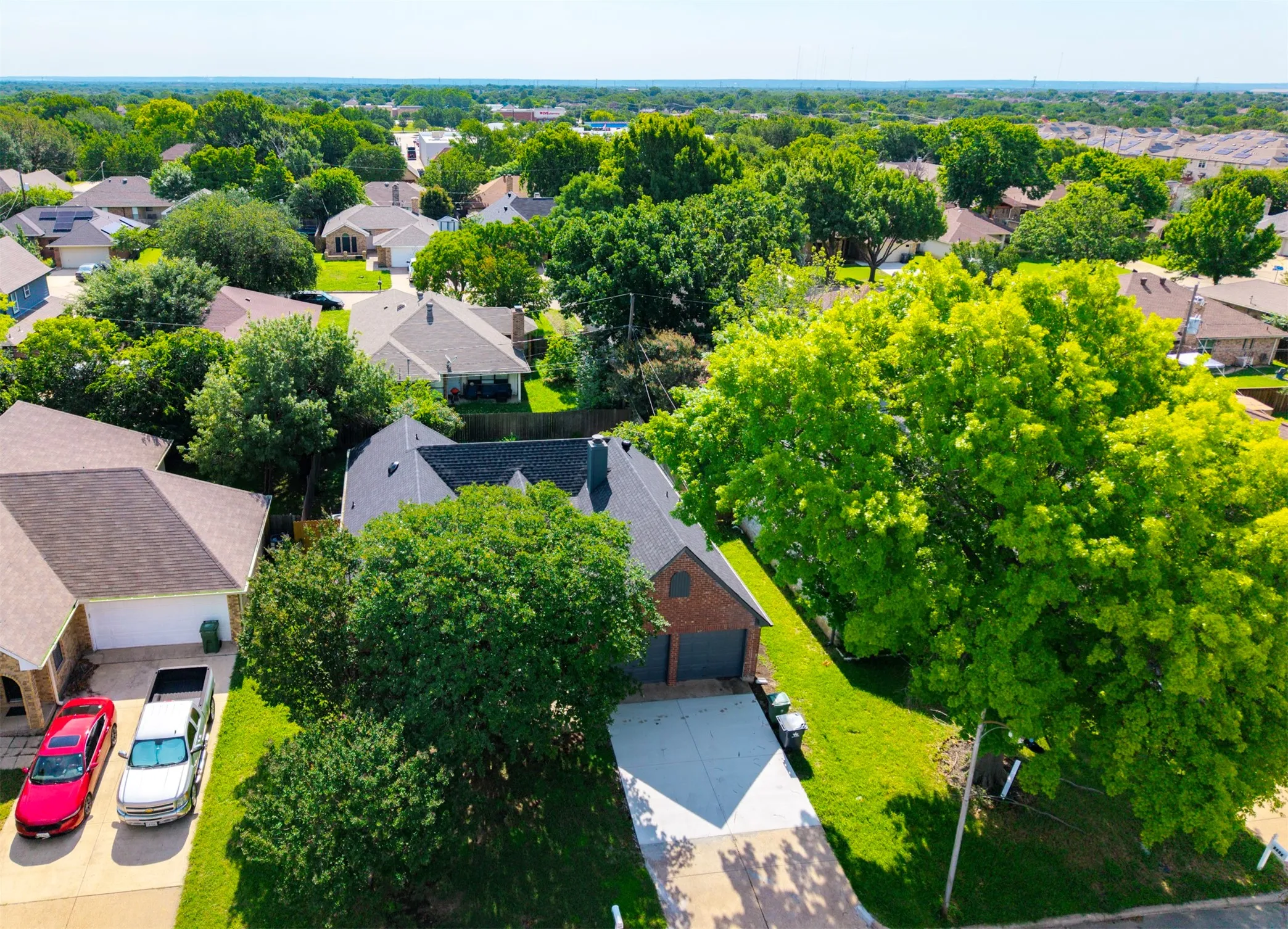 Brick exterior home featuring a dark shingle roof, attached garage with a double door, and a concrete driveway