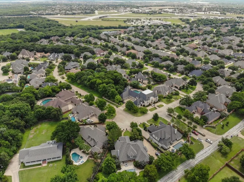 Aerial perspective showcasing a residential neighborhood with numerous single-family homes and abundant mature trees