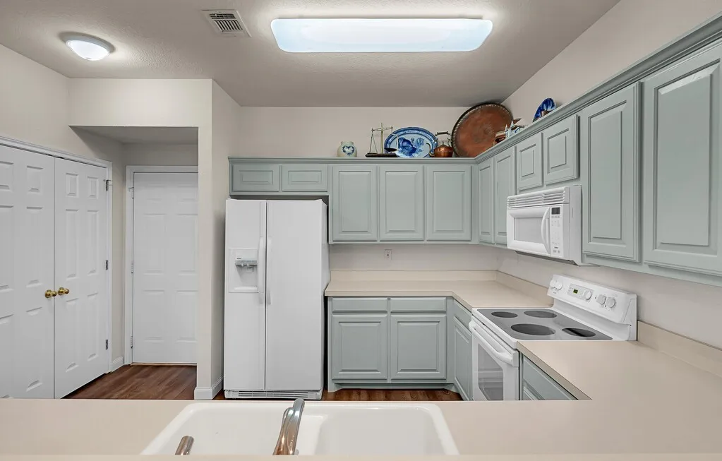 Kitchen with updated light green painted cabinetry.