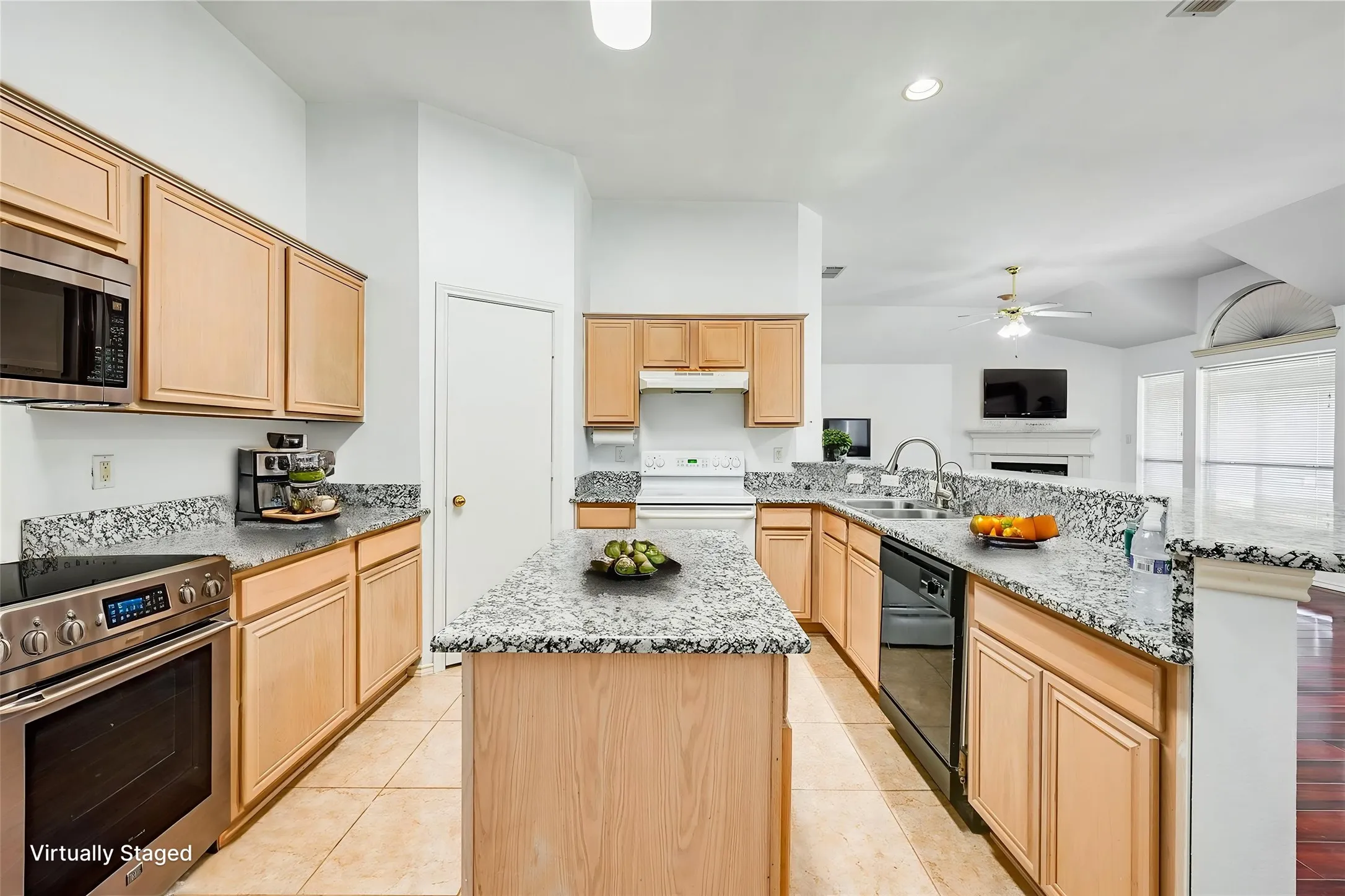 Kitchen featuring an island, light wood-finish cabinetry, stone countertops, stainless steel appliances, and tile flooring