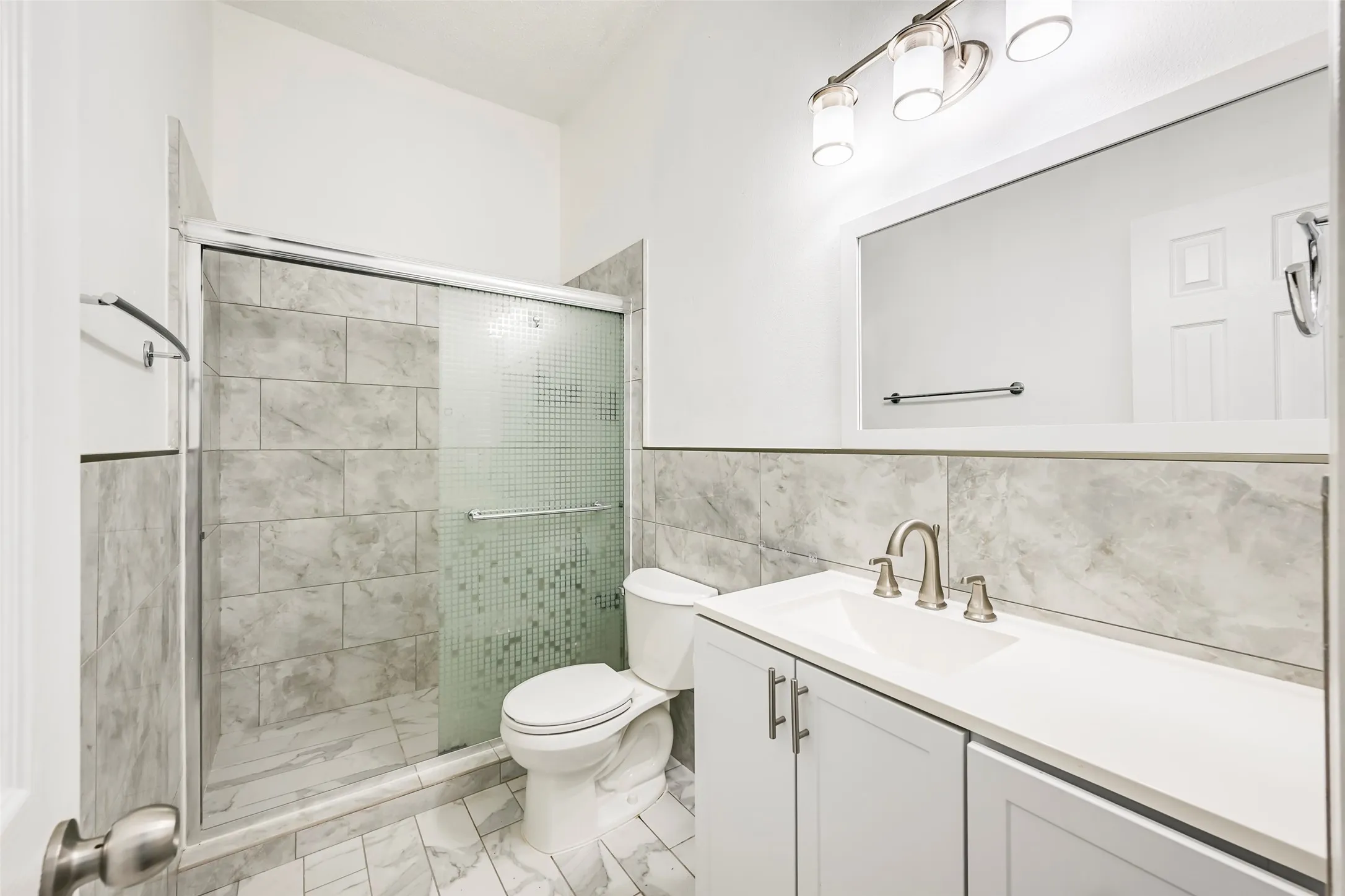 Modern bathroom featuring a vanity with a white countertop, brushed nickel faucet, and shaker-style cabinetry