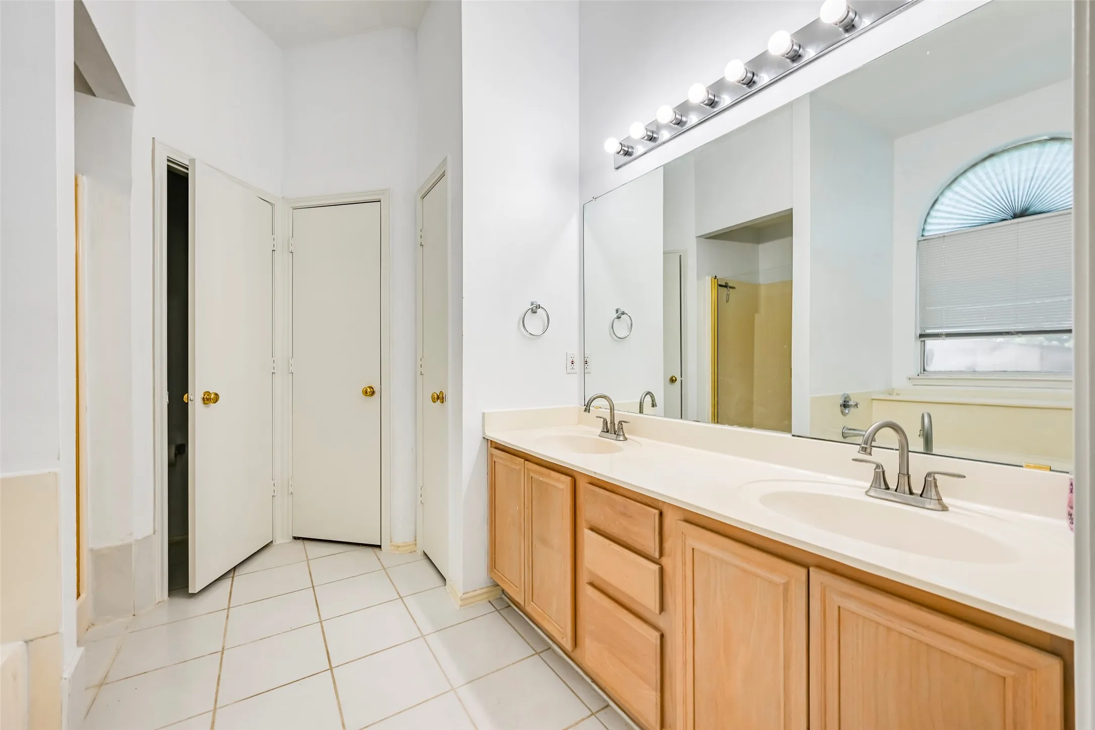 Double vanity featuring light wood-finish cabinetry, integrated sinks, and brushed nickel faucets
