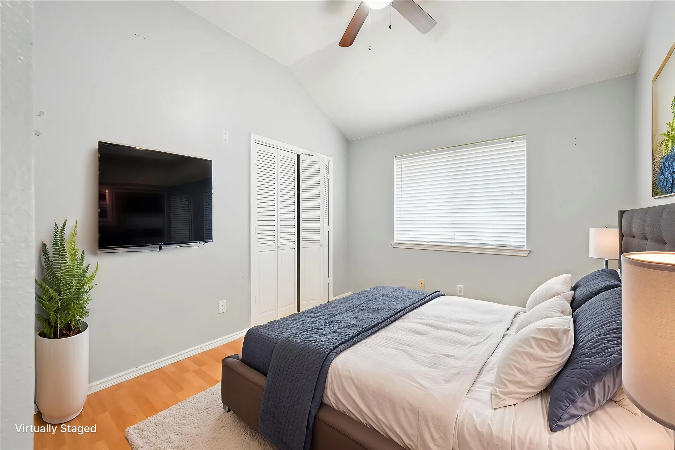 Vaulted ceiling, wood-finish flooring, ceiling fan, and white louvered bifold closet doors