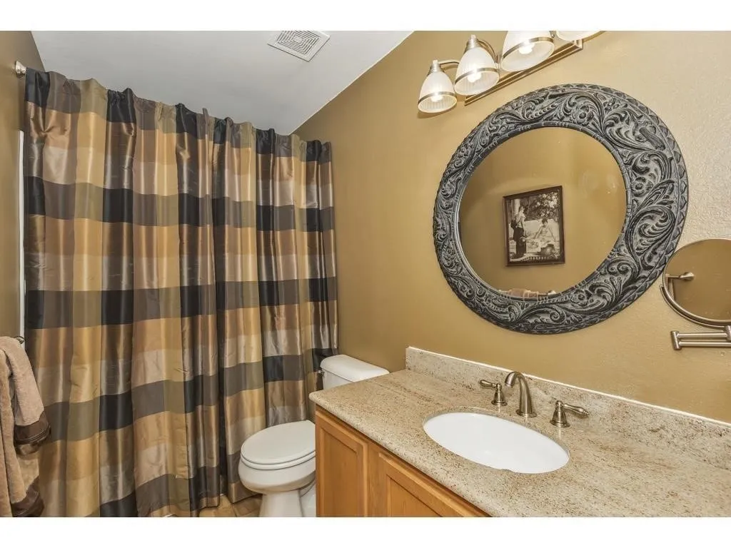 Bathroom featuring a light-toned vanity with an undermount sink, granite countertop, and brushed nickel faucet