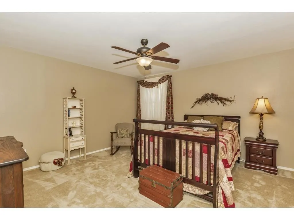 Bedroom featuring vaulted ceilings, ceiling fan with integrated lighting, carpeted flooring, and a window with valance