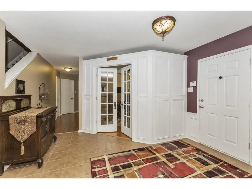 Foyer featuring ceramic tile flooring, white panel French doors, and built-in white cabinetry