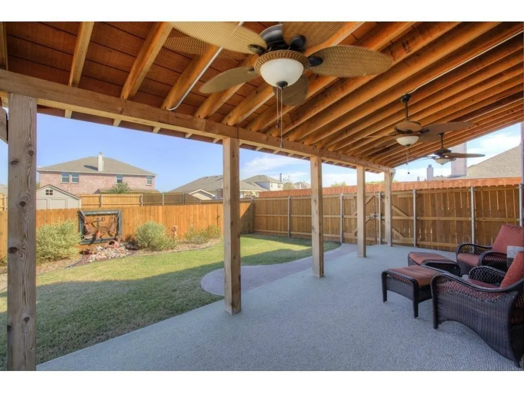Expansive covered patio featuring an exposed wood beam ceiling and multiple ceiling fans