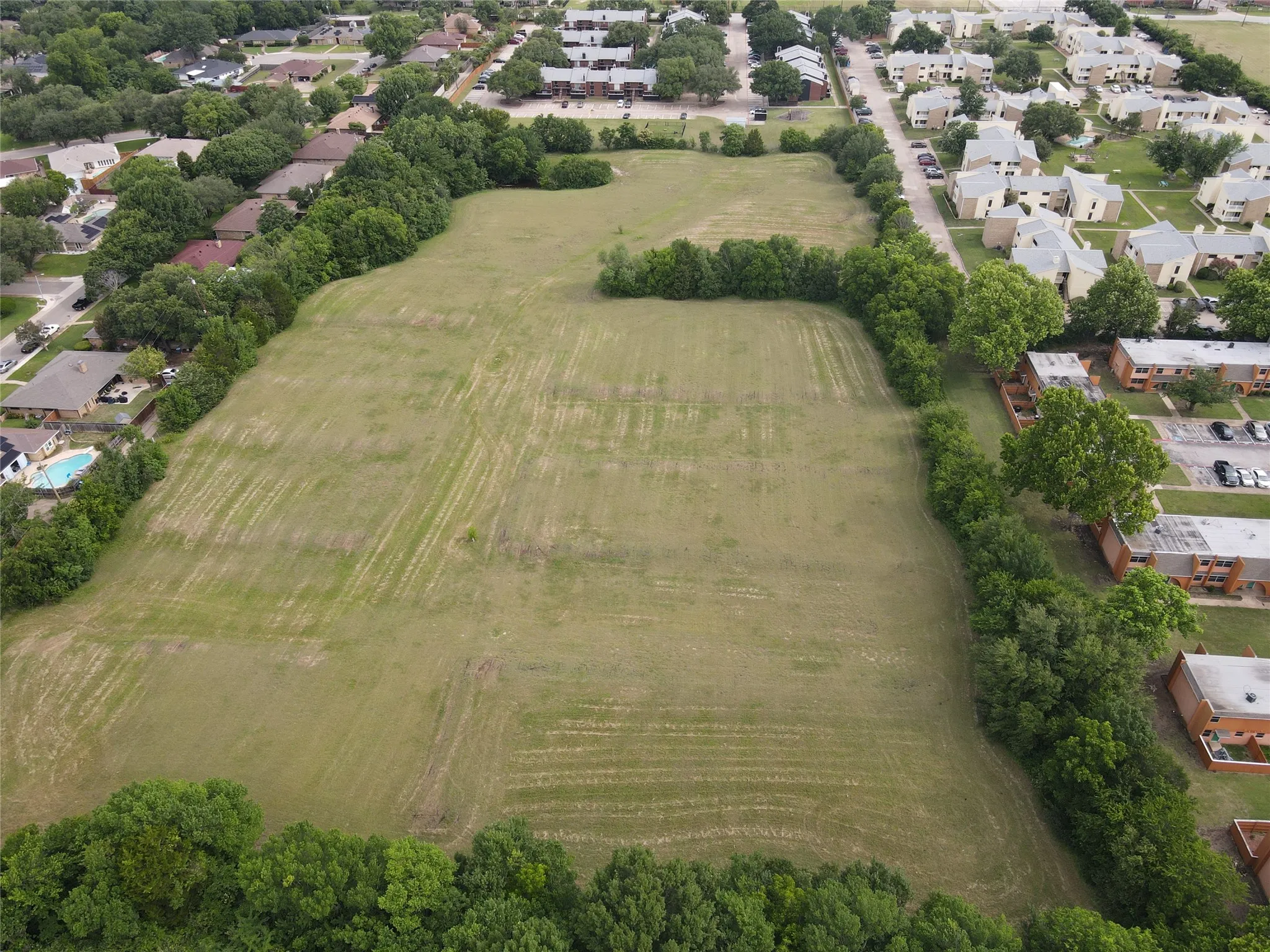 Expansive land parcel featuring a perimeter of mature trees