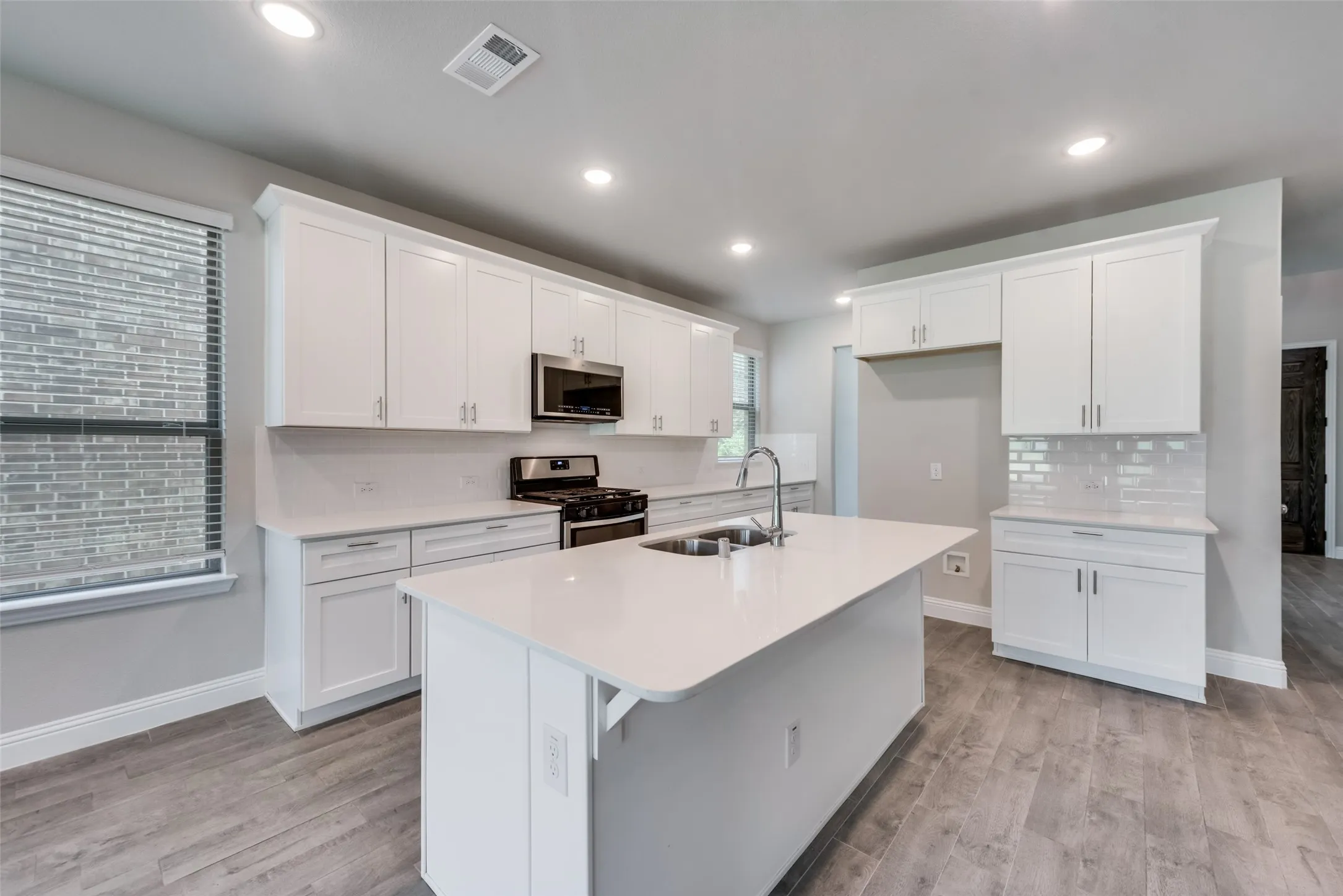 Contemporary kitchen featuring an expansive central island with an undermount sink and a gooseneck faucet