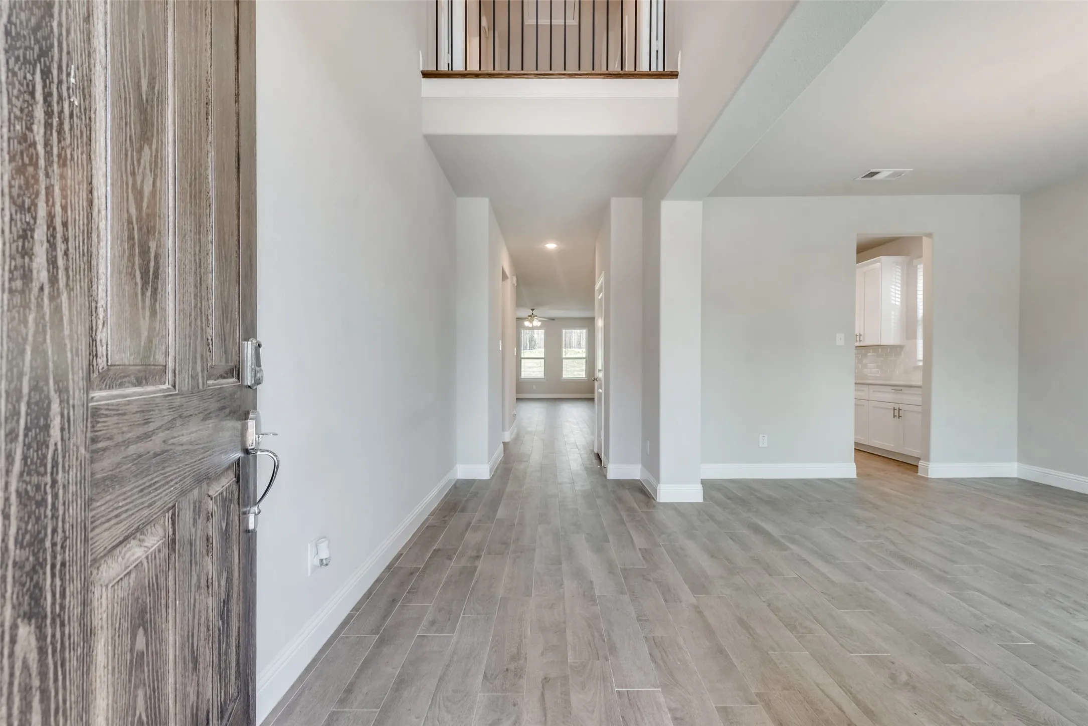 Entryway featuring a wood-look plank tile floor, white baseboards, and a contemporary grey wood-grain door