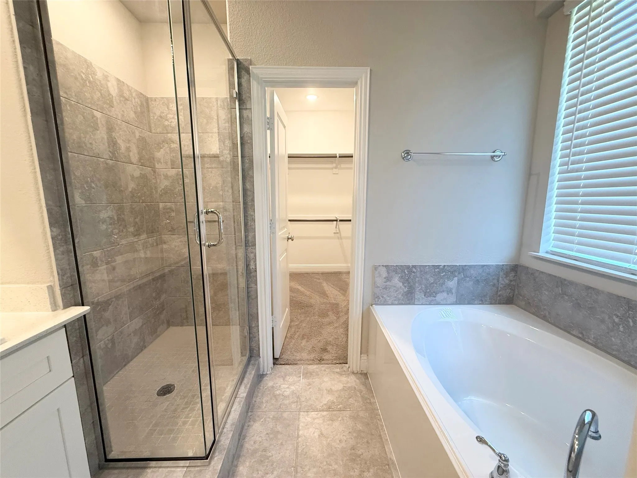 Contemporary bathroom featuring a glass-enclosed shower with tile surround, a built-in bathtub with tile wainscoting, and tile flooring