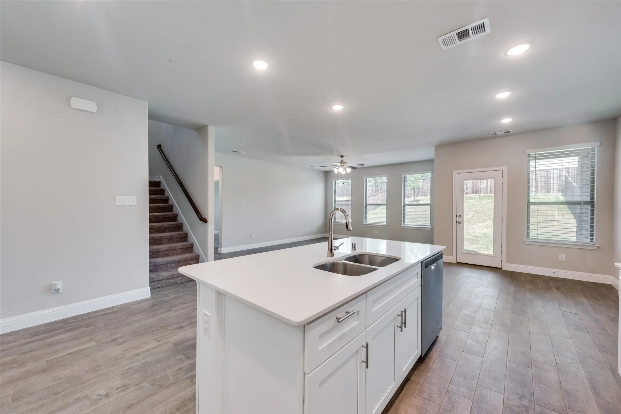 Kitchen island featuring a double-basin stainless steel sink, a gooseneck faucet, and white cabinetry with brushed nickel hardware
