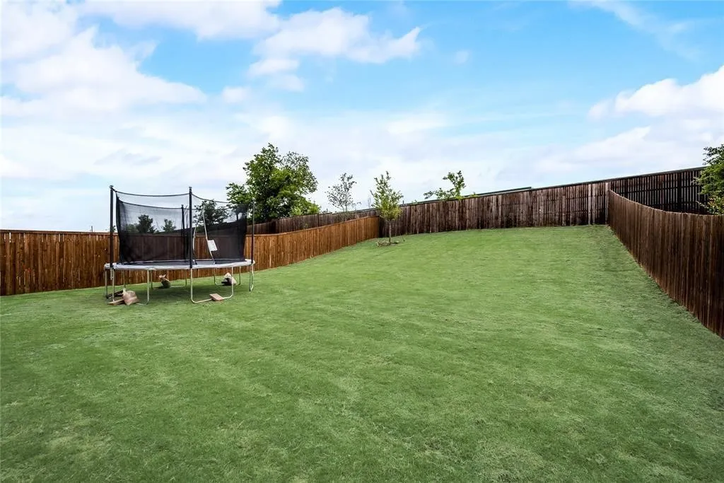 Expansive green lawn surrounded by a privacy fence, with a gentle slope