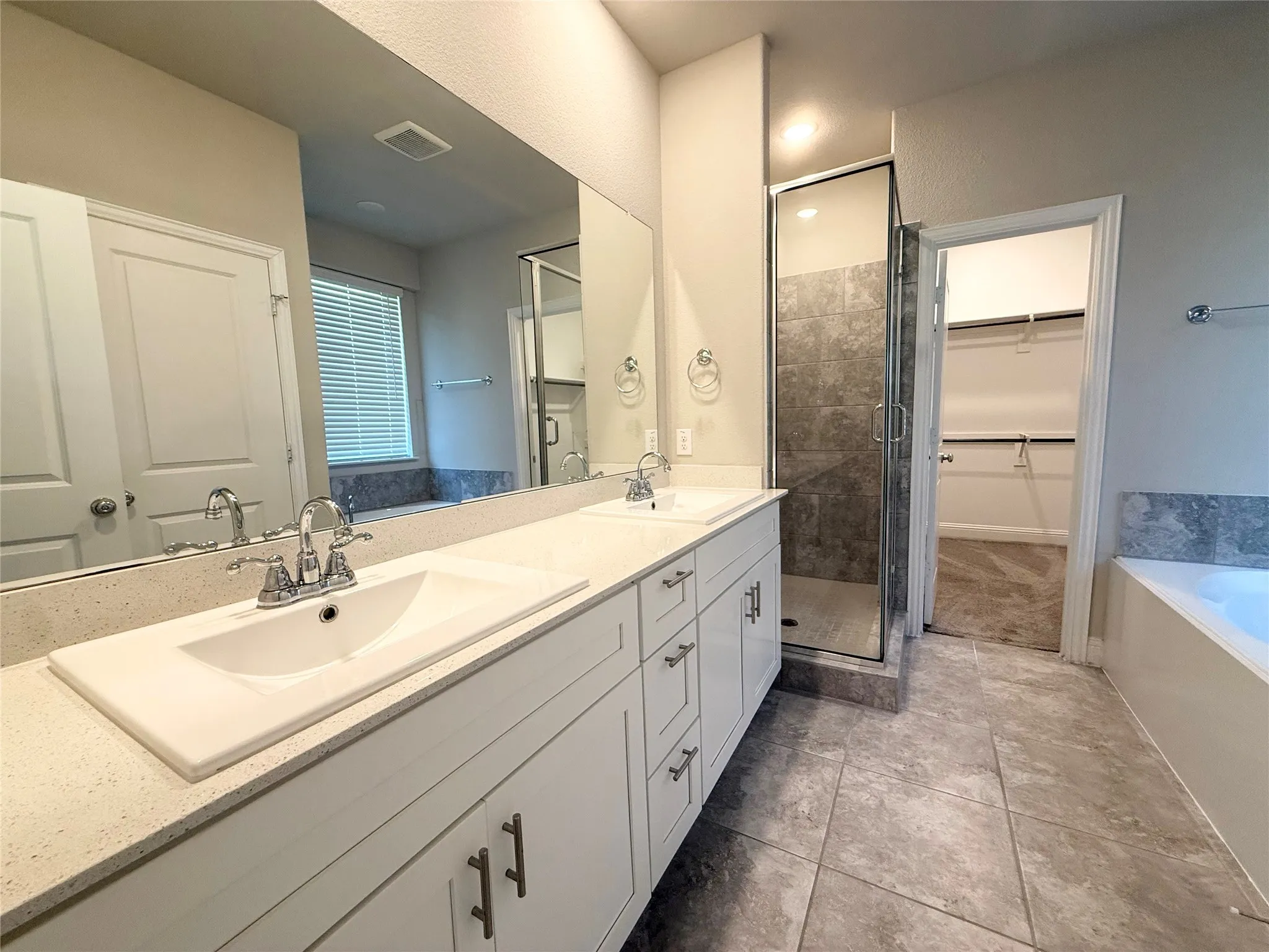 Dual vanity with integrated sinks and chrome fixtures, quartz-finish countertop, and white cabinetry