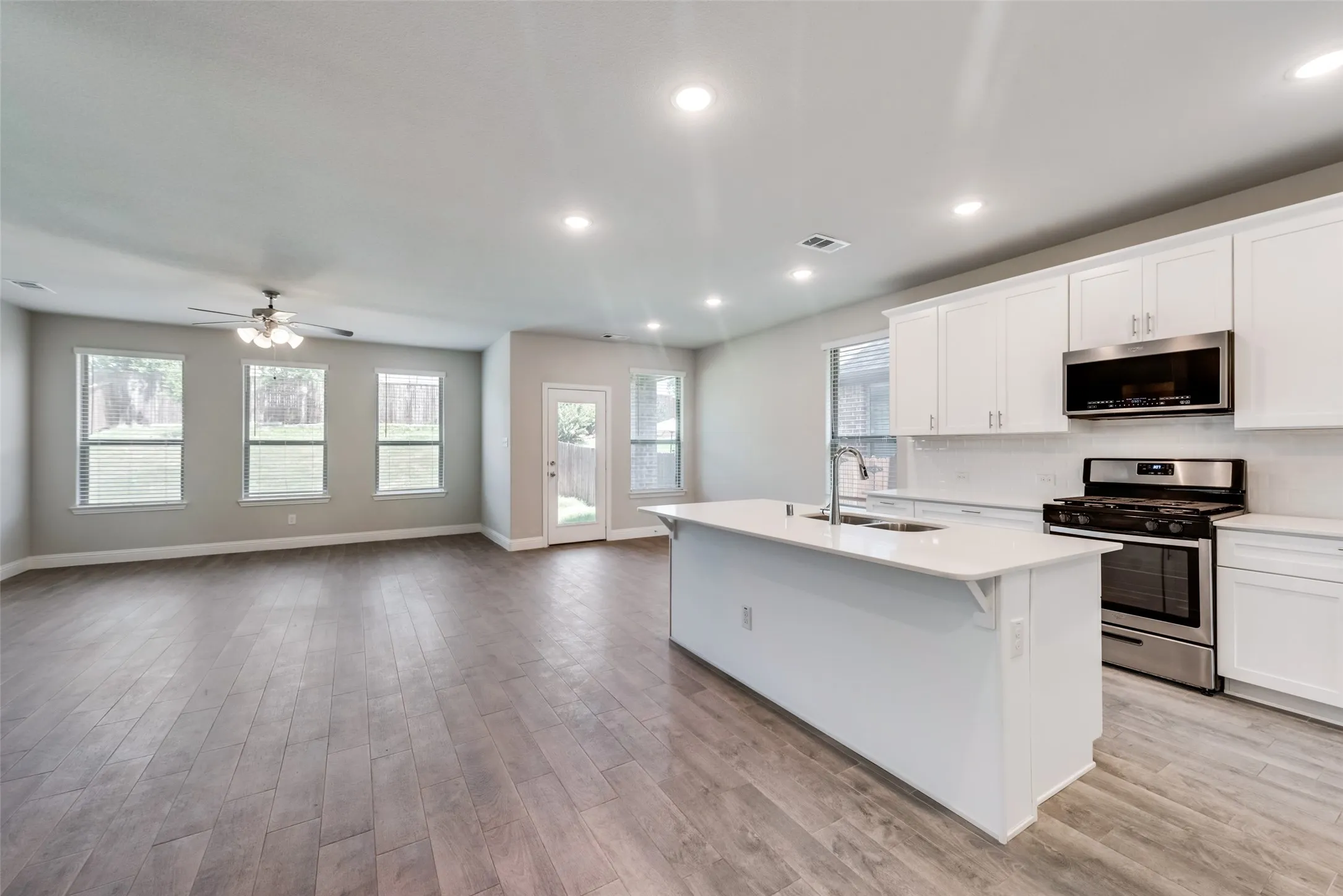 Open-concept interior featuring wood-finish flooring, recessed lighting, and a ceiling fan
