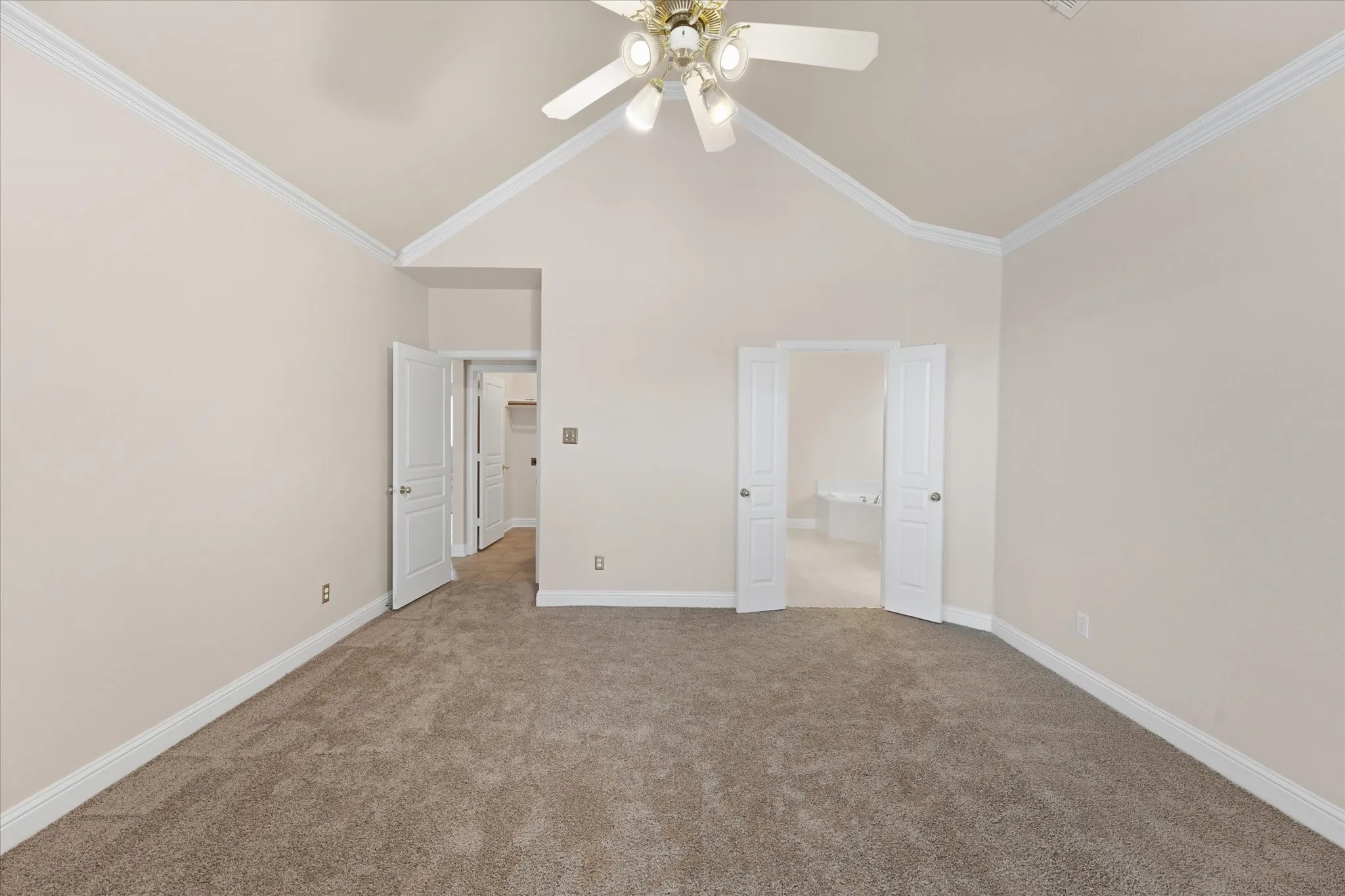 Vaulted ceiling, ceiling fan, crown molding, double door entry, and wall-to-wall carpeting