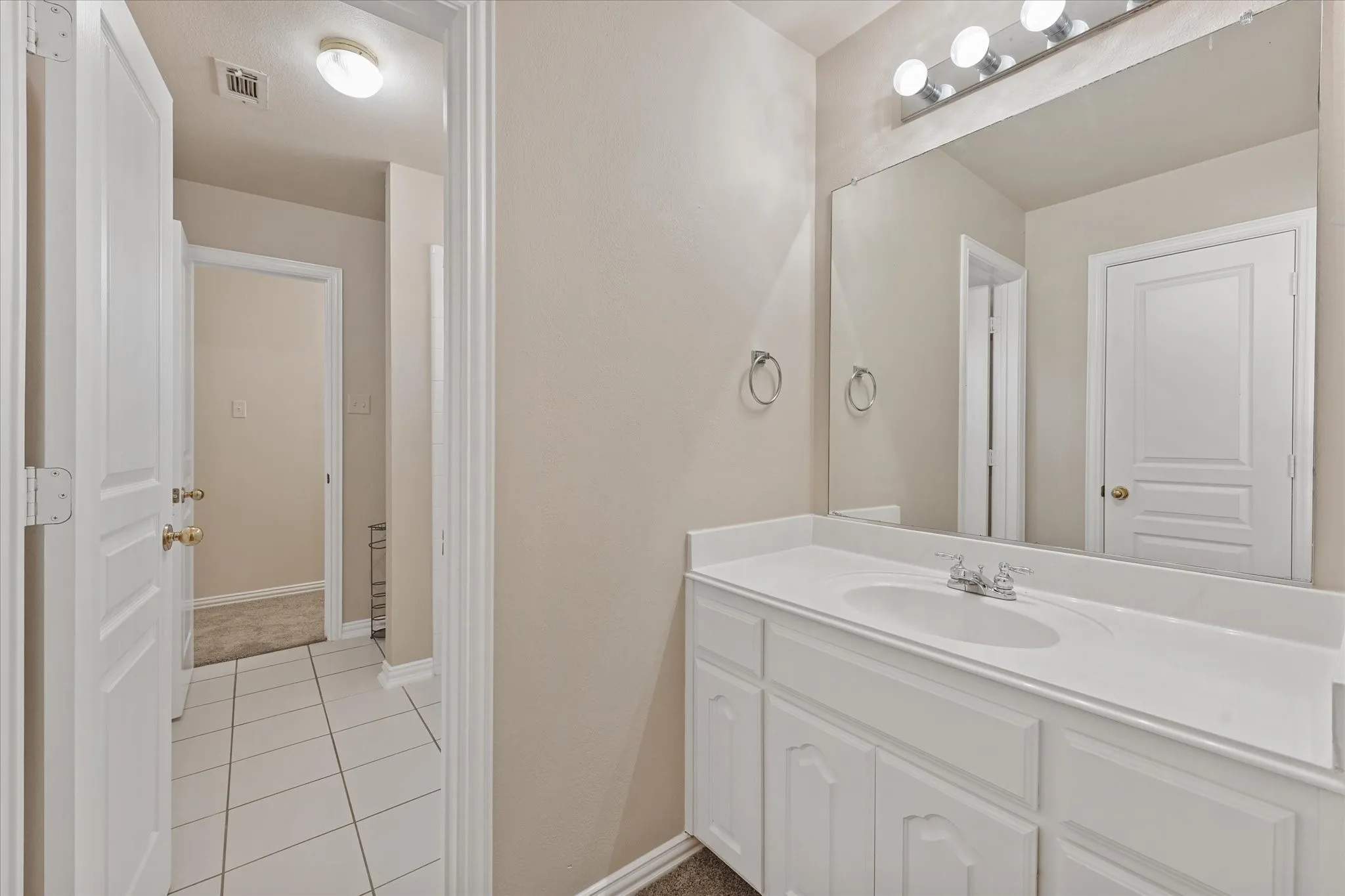 Vanity with an integrated sink, polished chrome faucet, and expansive mirror